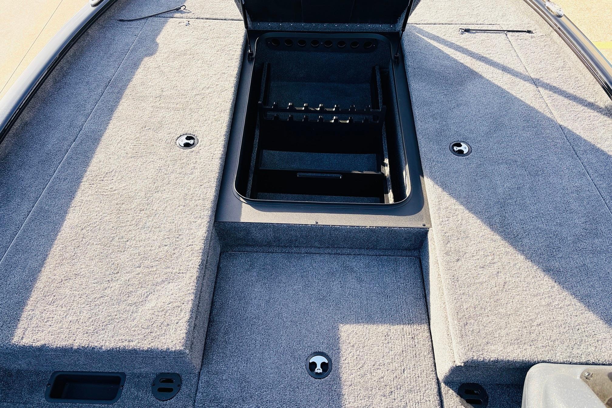 2025 Tracker Savage 215 boat deck with open storage compartment, gray carpeted surface.