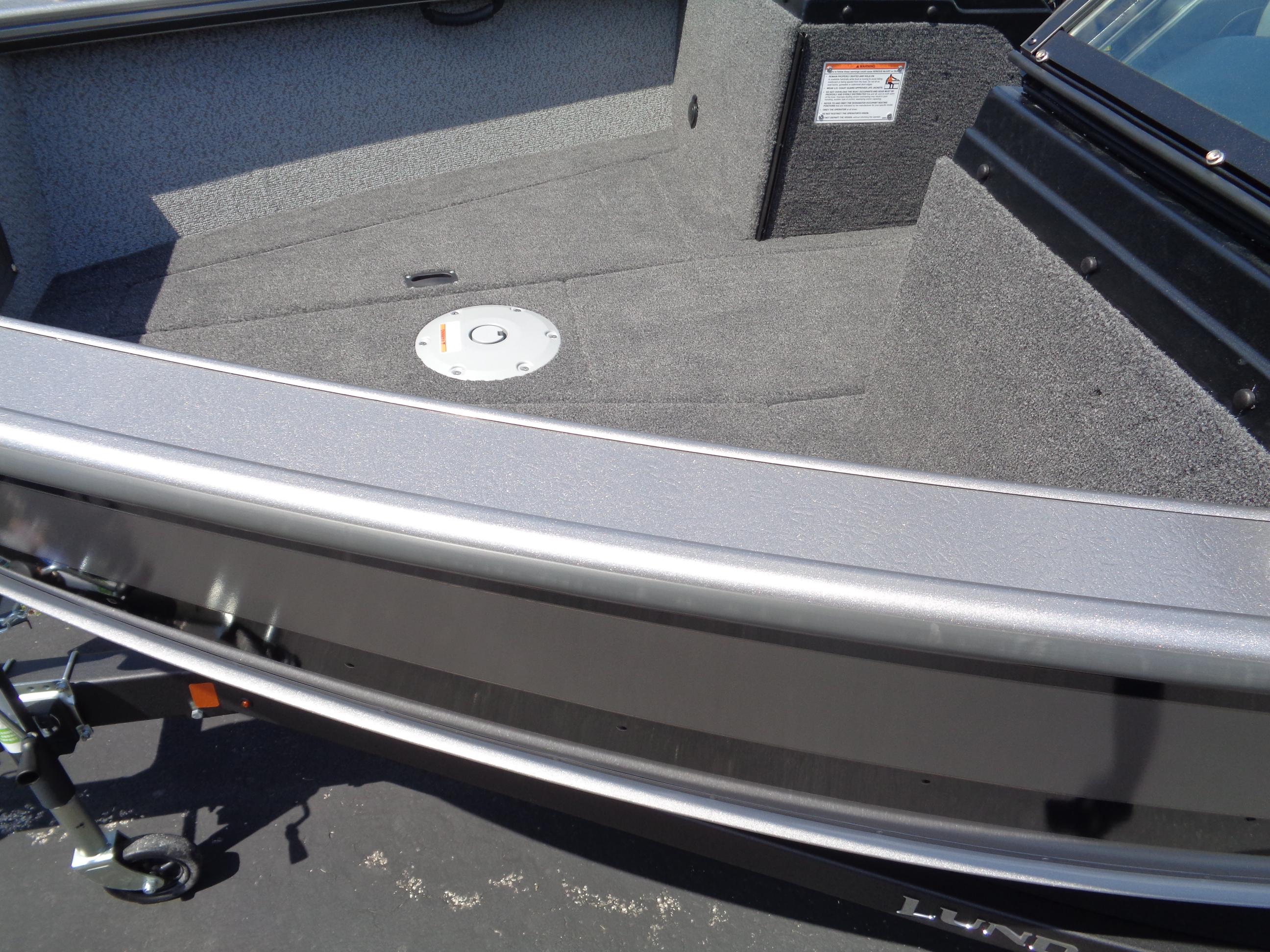 2025 Lund 2075 Fisherman boat interior with carpeted deck and storage compartment.