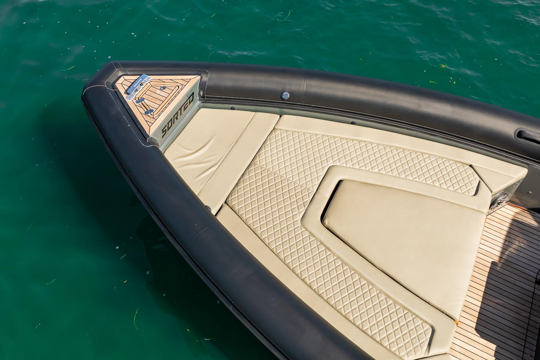 Bow of 2023 Skipper-BSK 38NC boat with beige quilted seating on turquoise water.