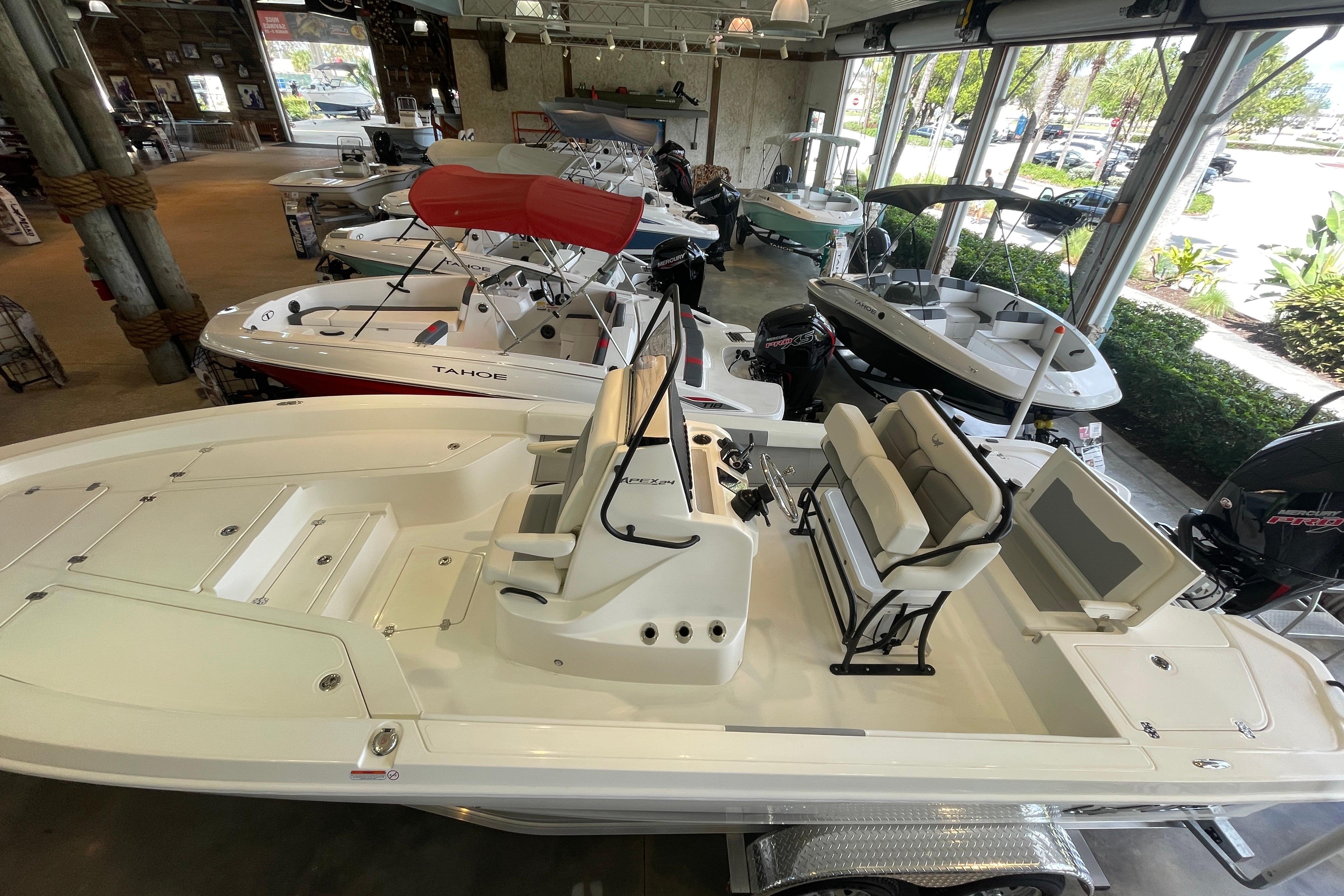 2026 Mako 24 APEX boat displayed in showroom, featuring sleek design and spacious seating.