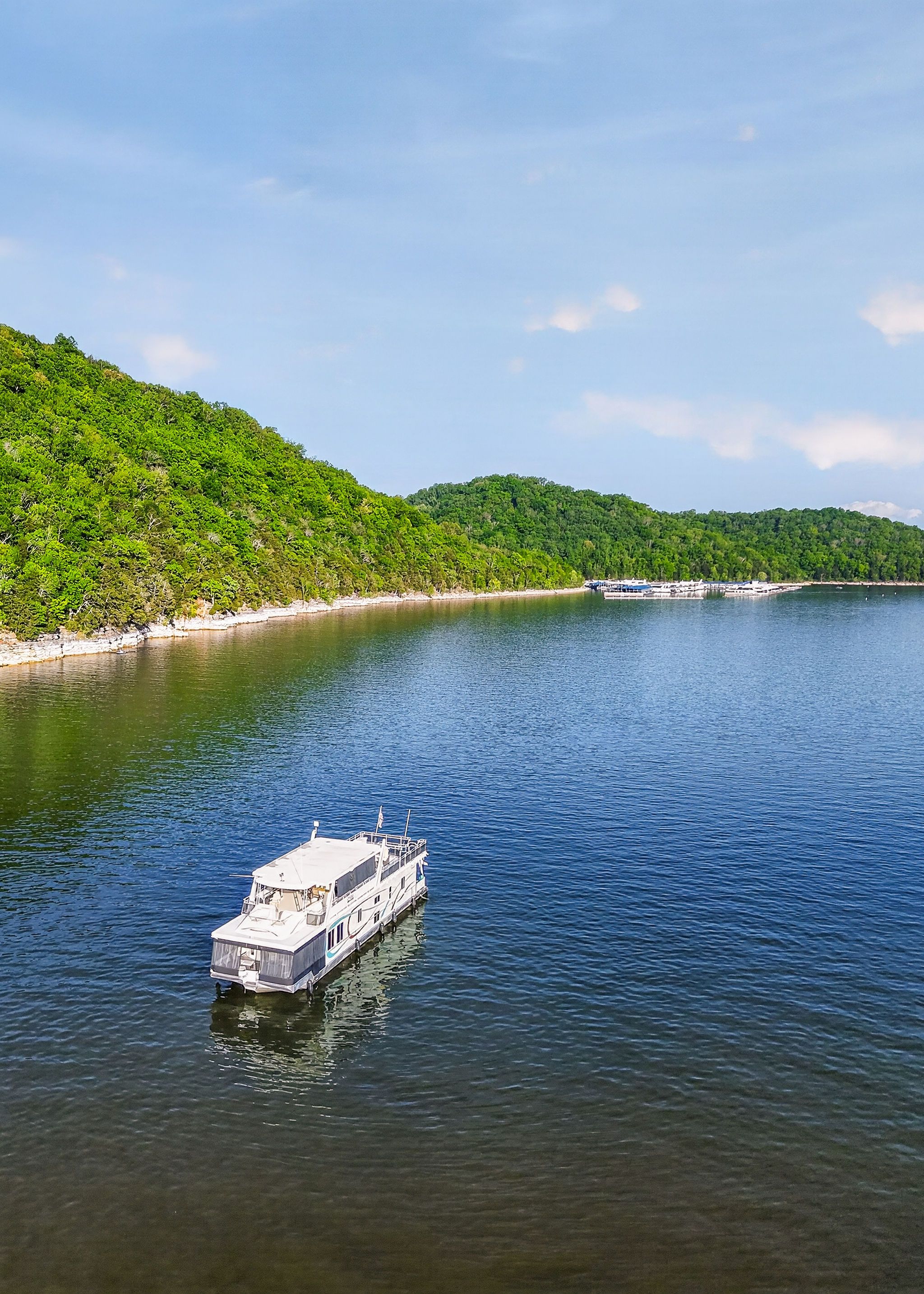 Houseboat on serene lake with wooded shores, Thoroughbred model 2010.