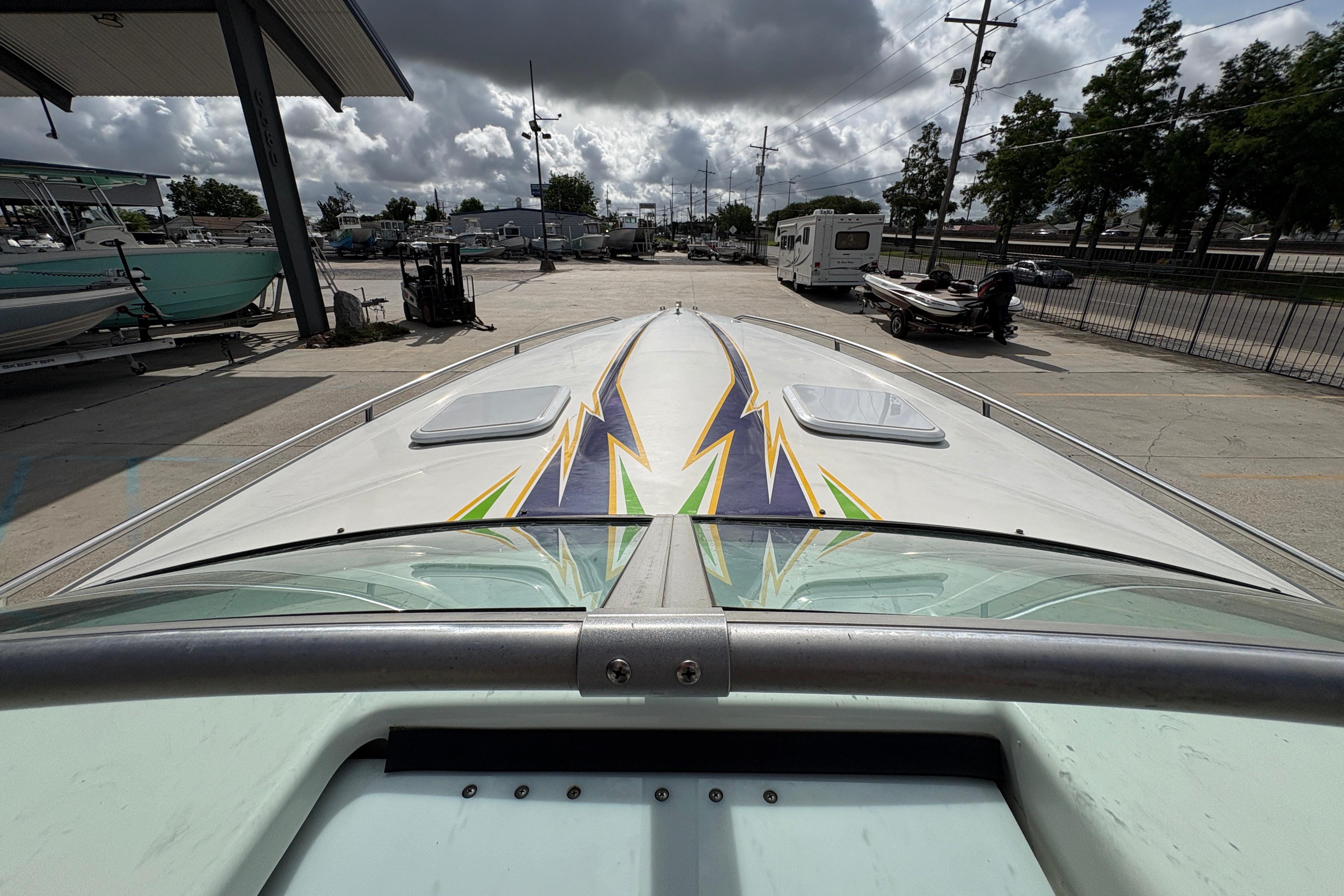 2002 Formula 292 FASTech boat with vibrant lightning graphics, parked at a marina under cloudy skies.