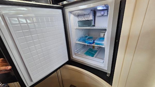 Open refrigerator on 2005 Neptunus 56 Flybridge yacht, showing organized interior shelves.