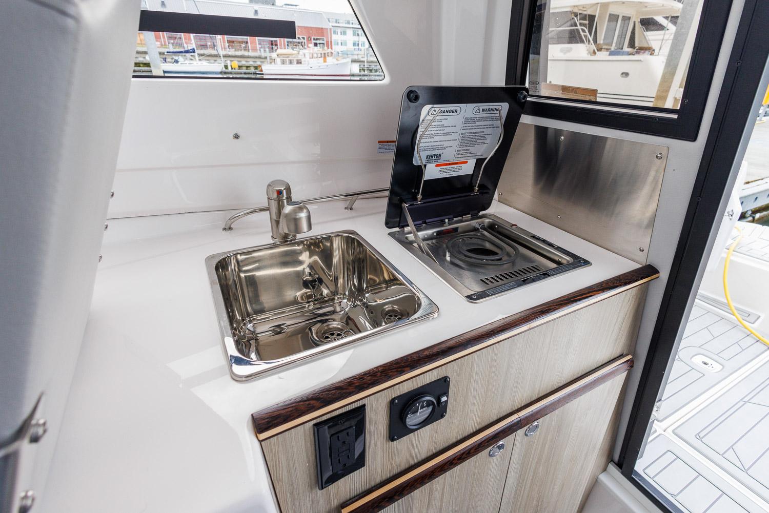 Compact kitchen area in 2026 Solara 250-C boat with sink and stove.