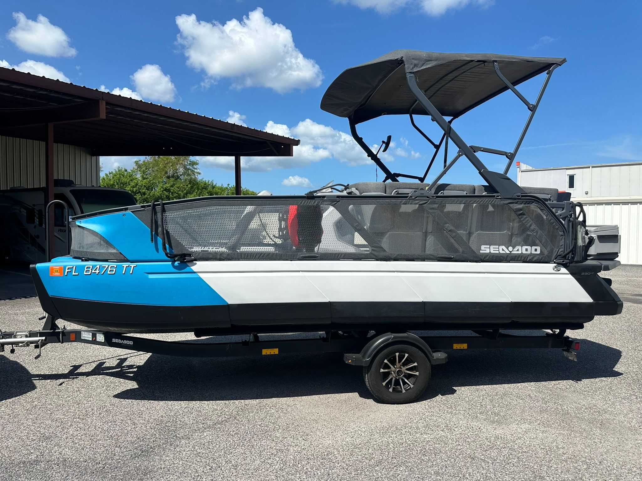 A 2023 Sea-Doo 21 SWITCH SPORT on a trailer, featuring a blue and white hull and black sunshade.