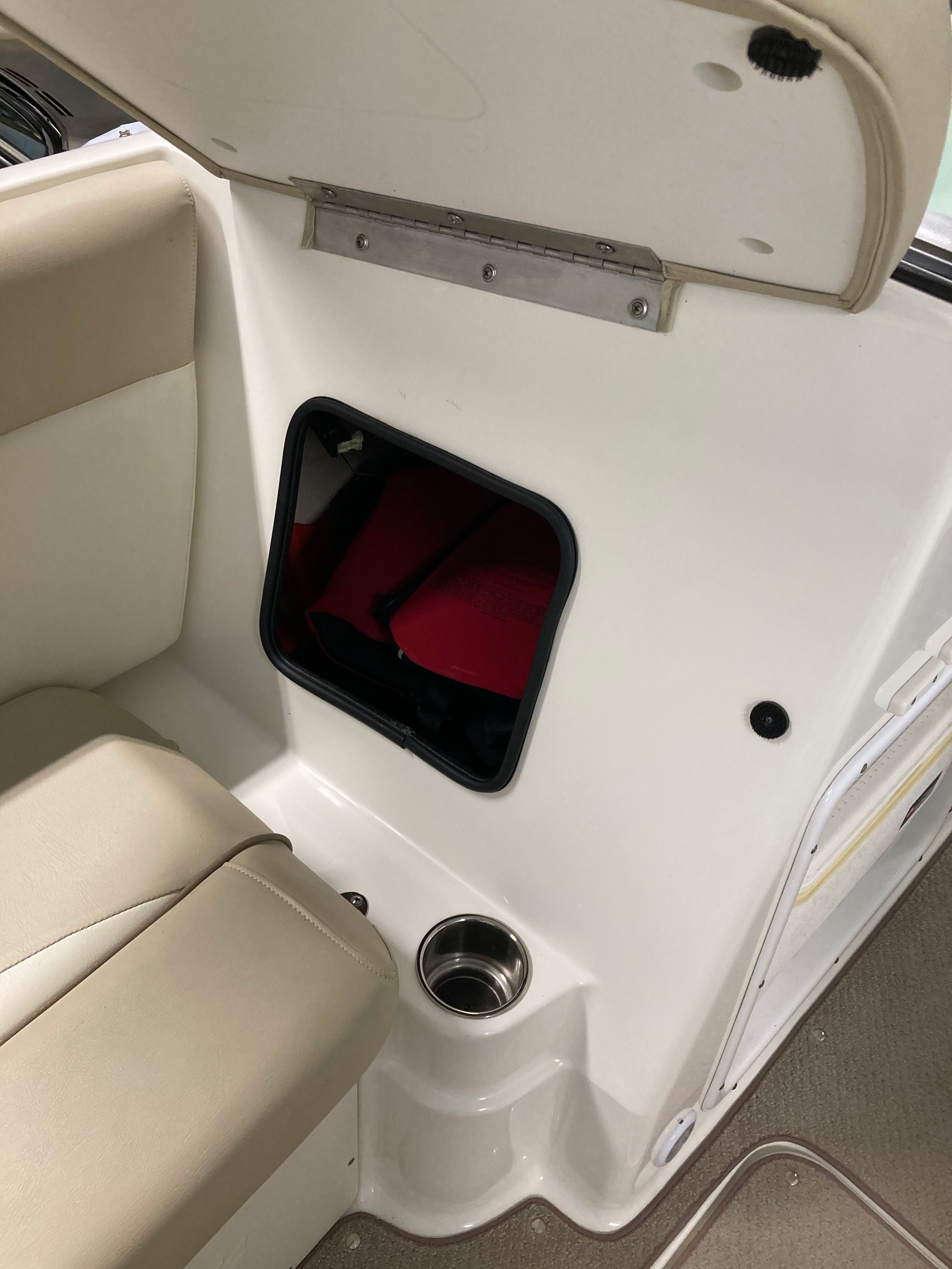 Interior of a 2016 Custom 223 DC boat with seating and storage compartment.