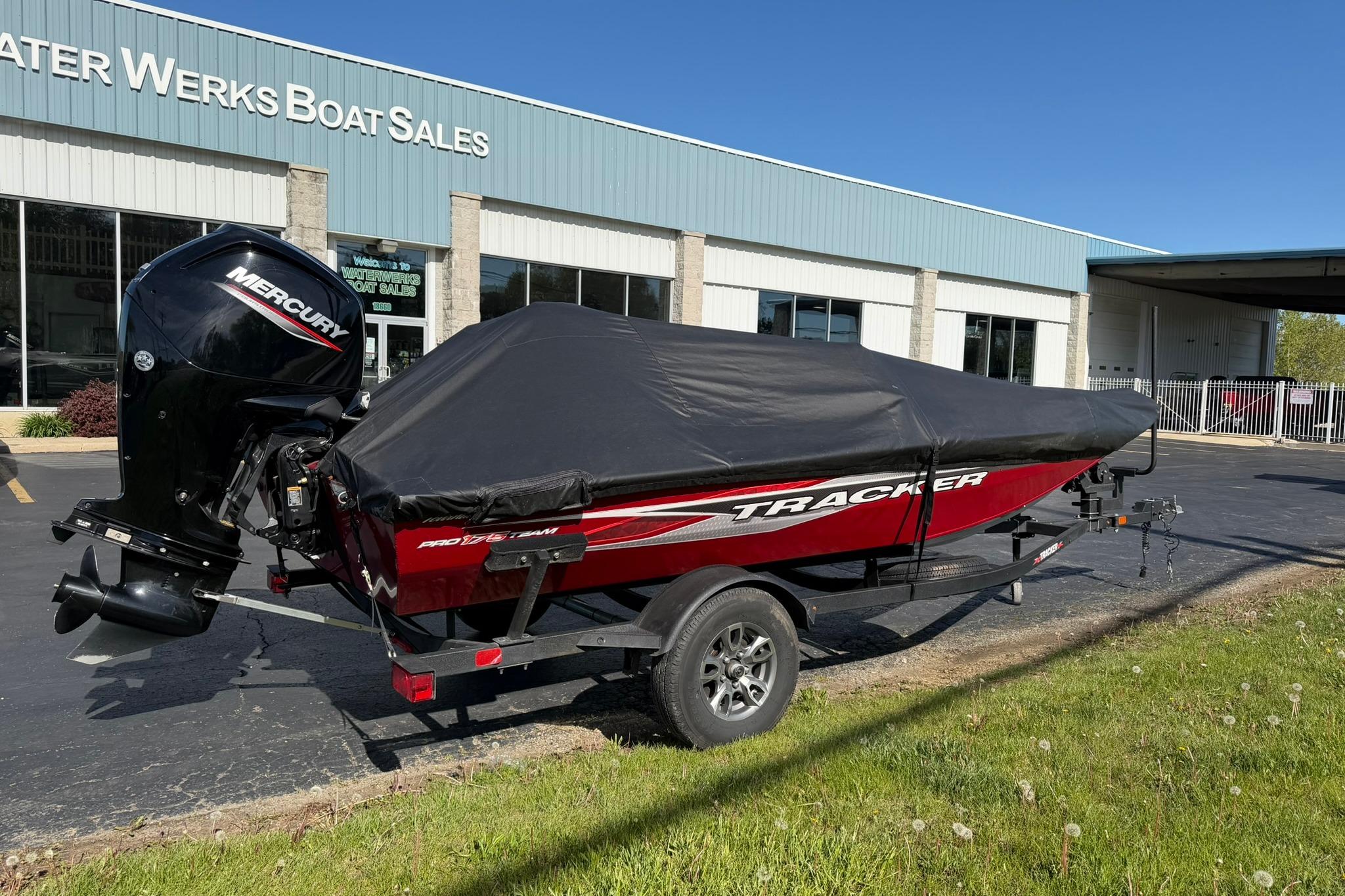 2024 Tracker Pro Team 175 TXW boat with cover at dealership, featuring Mercury outboard motor.