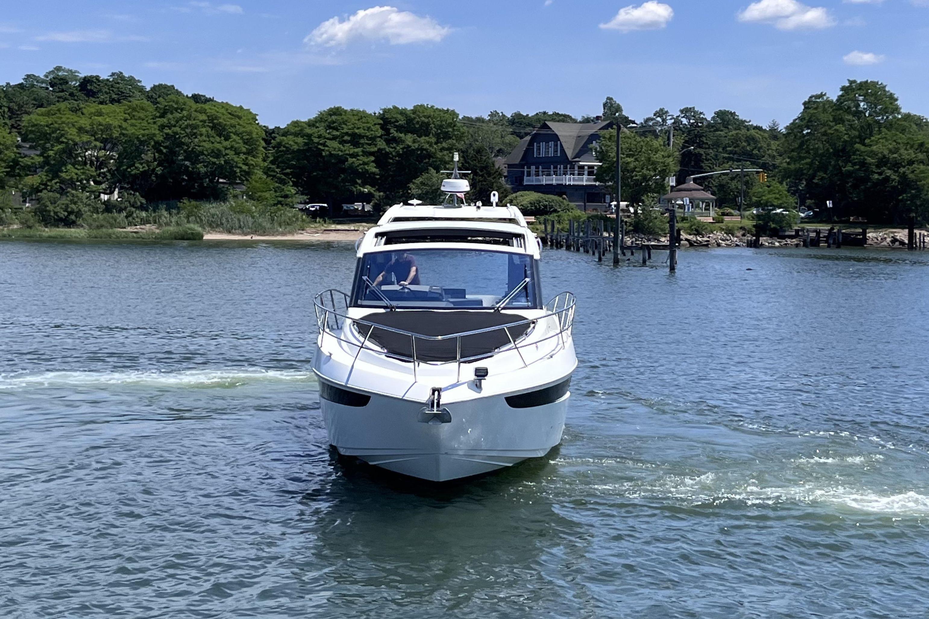 2024 Galeon 425 HTS yacht cruising on a serene lake with lush greenery.