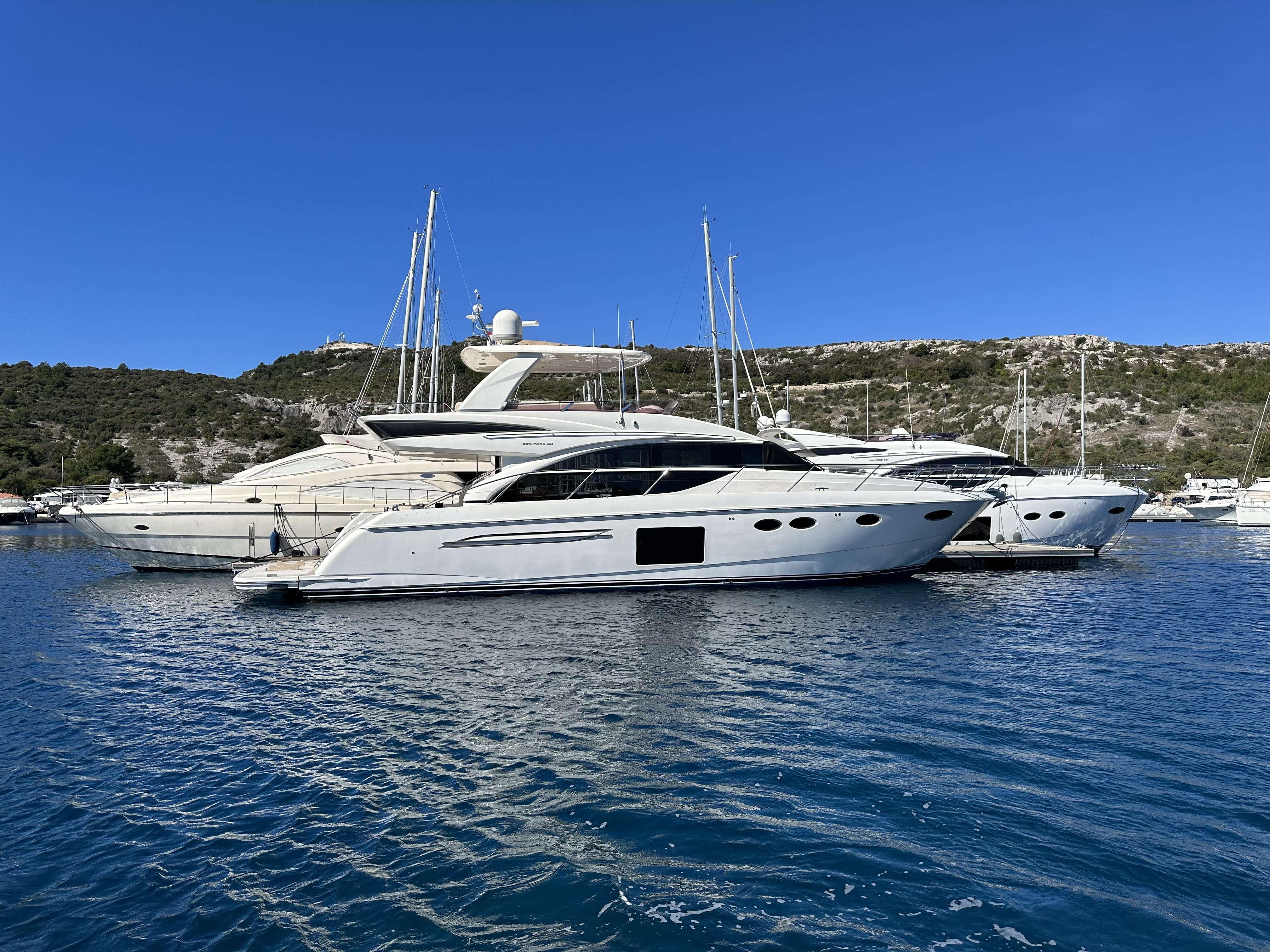2014 Princess 60 yacht docked in a serene marina under a clear blue sky.