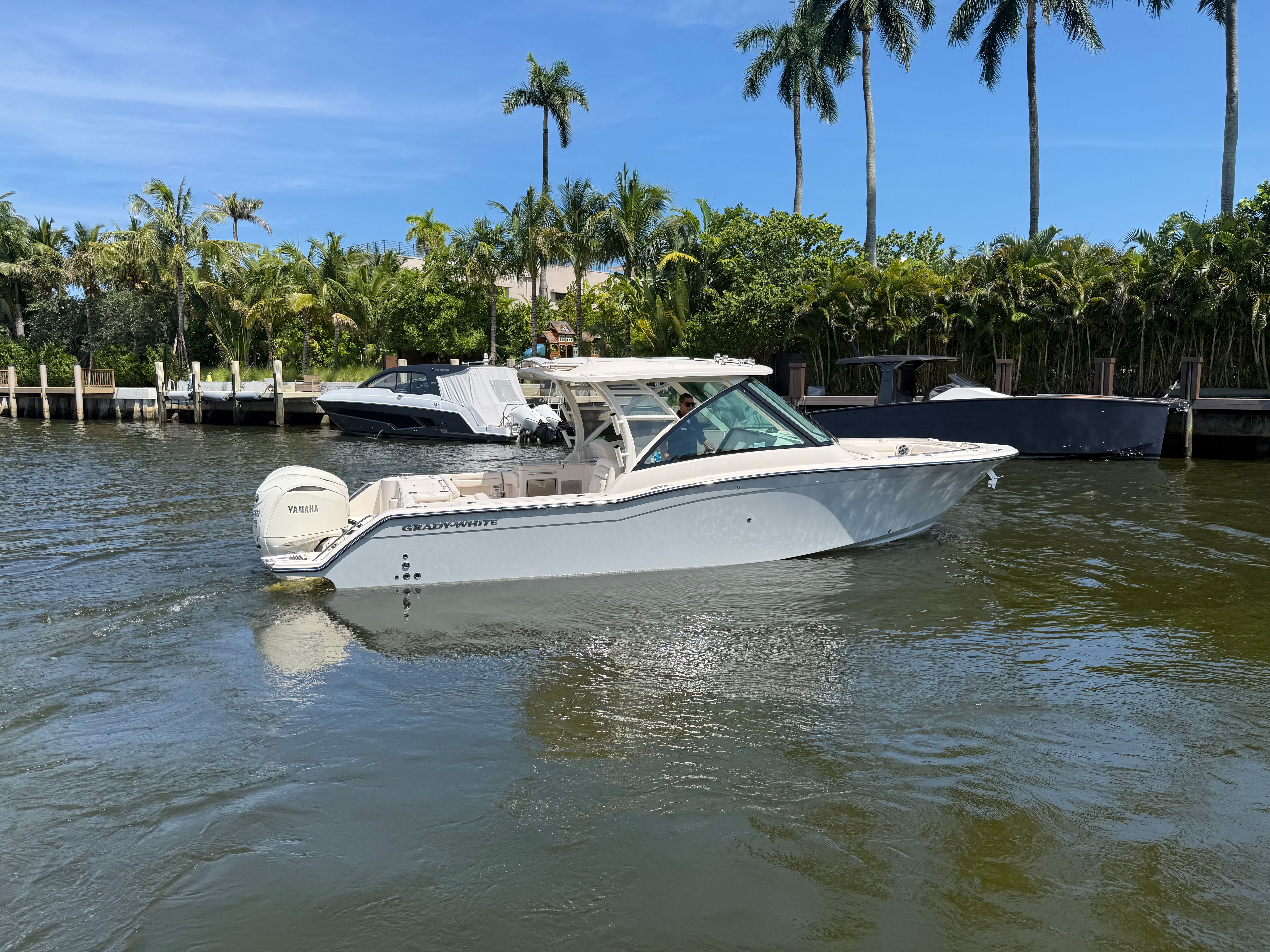 A Grady-White Freedom 325 boat on the water, surrounded by palm trees and other boats.