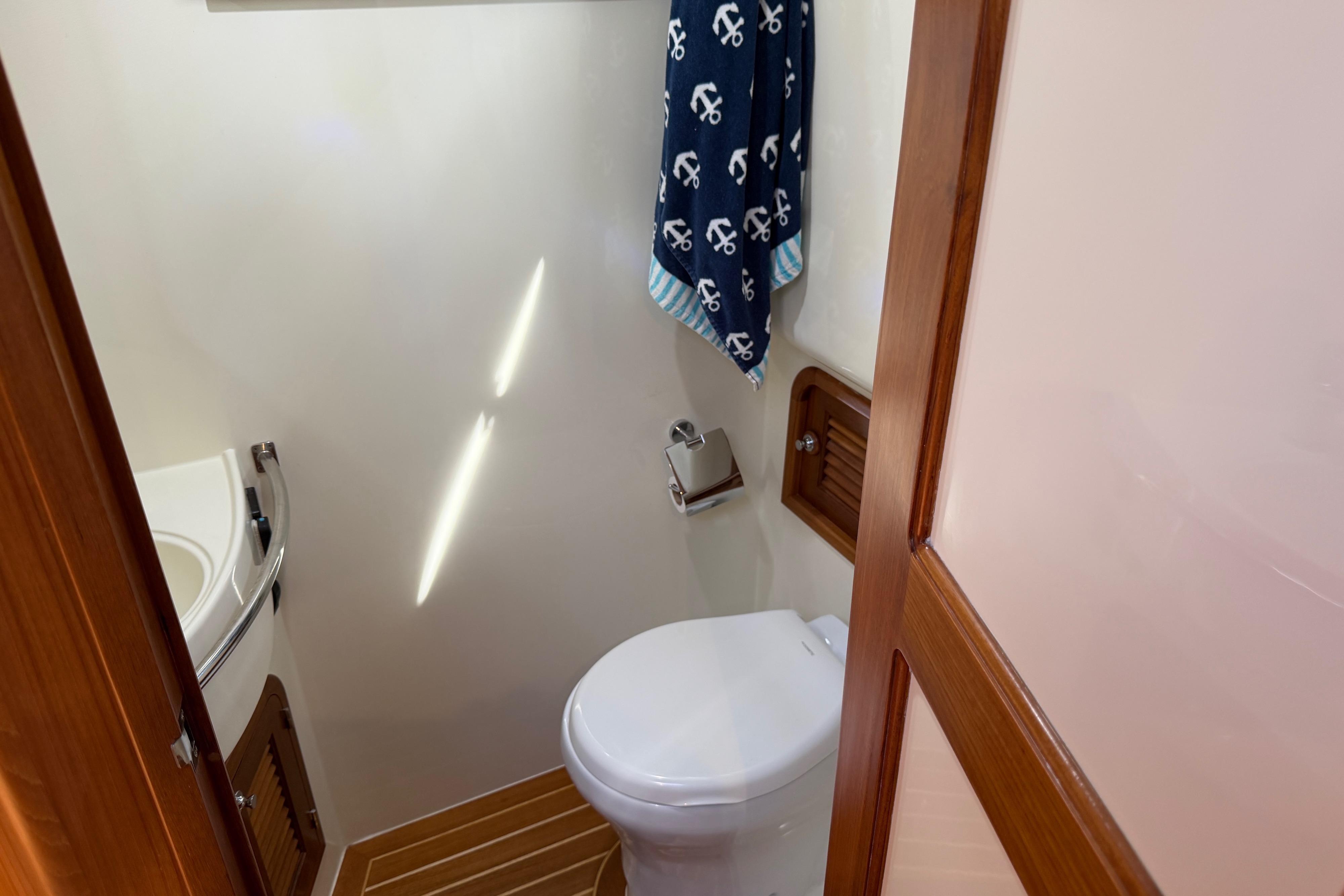 2020 Helmsman Trawlers 38E bathroom with toilet, sink, and nautical-themed towel.