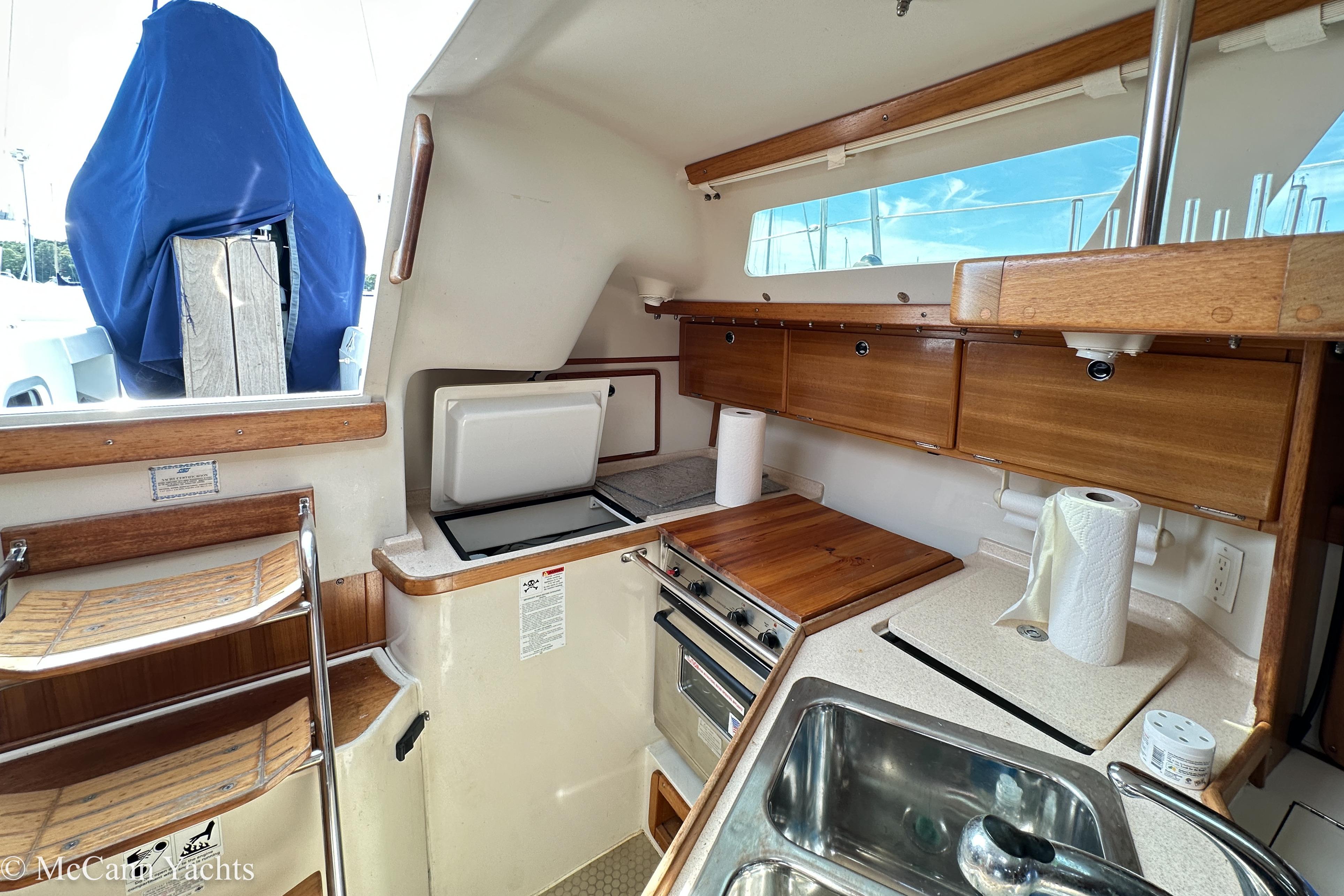 Interior of 2003 Catalina 320 yacht kitchen with wooden cabinets and stainless steel sink.