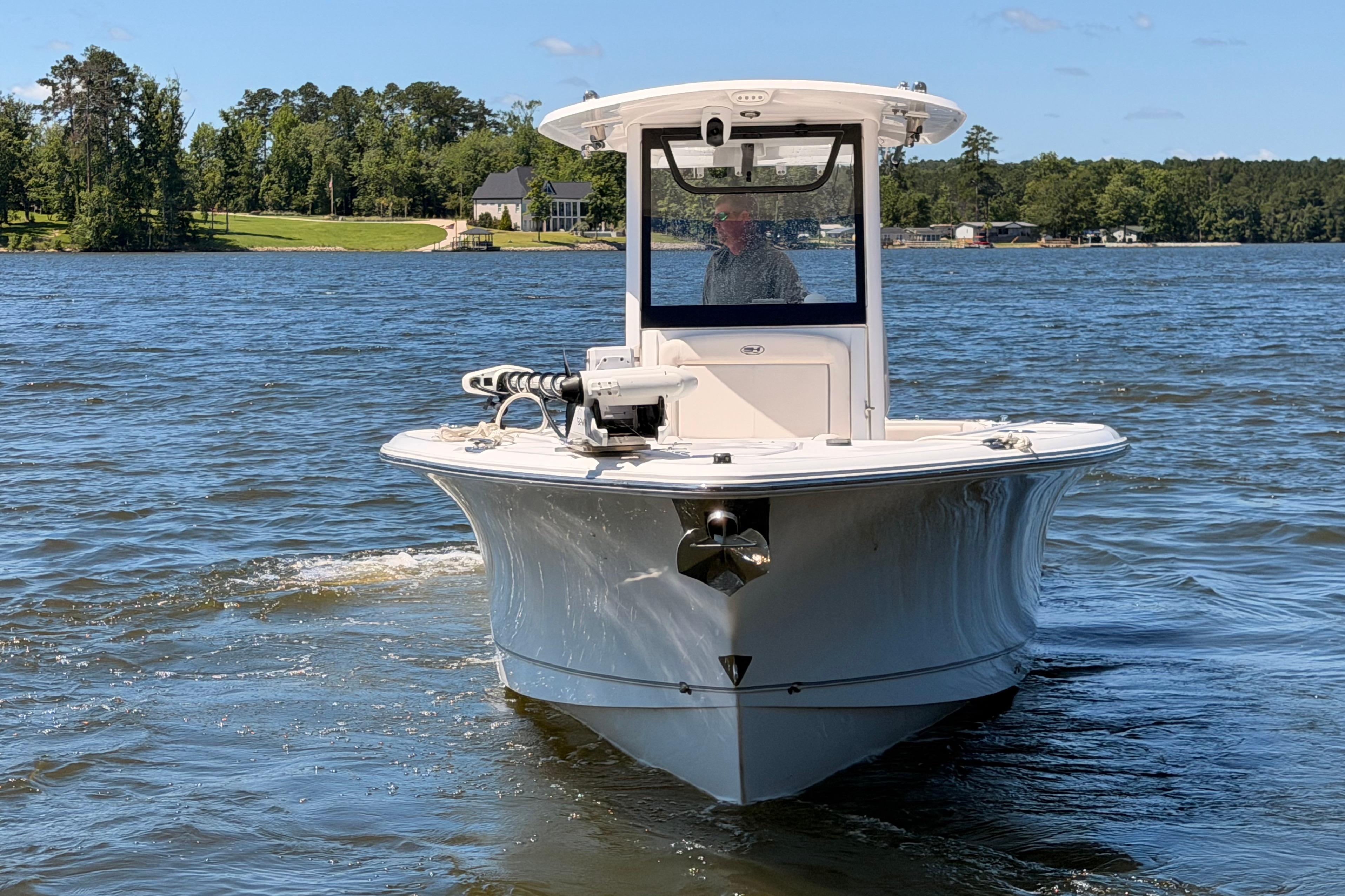 2024 Sea Hunt Gamefish 27 Coffin Box boat cruising on a scenic lake.