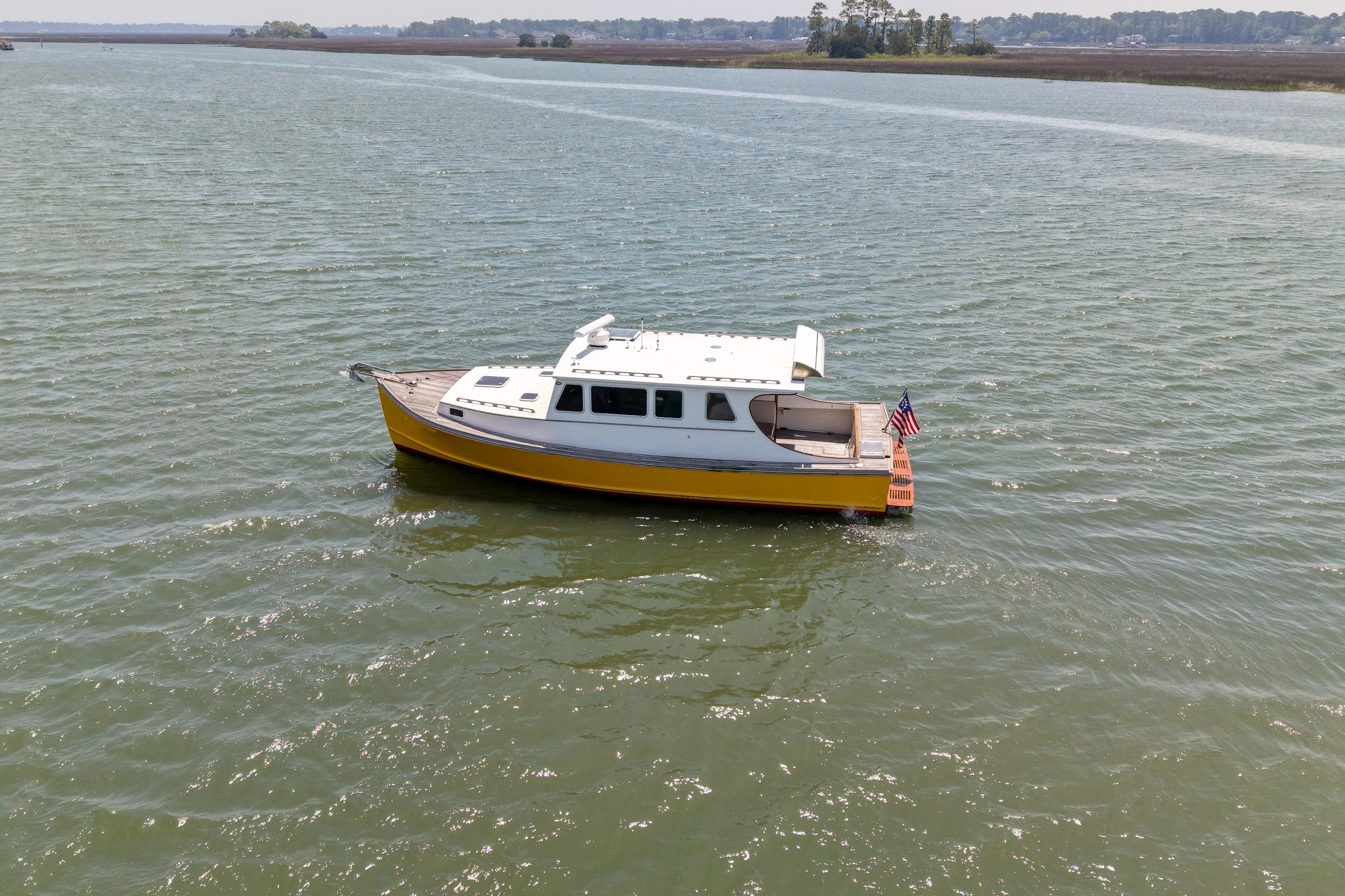 Yellow Redfern Mitchell Cove 32 boat from 2001 on calm water, American flag displayed.