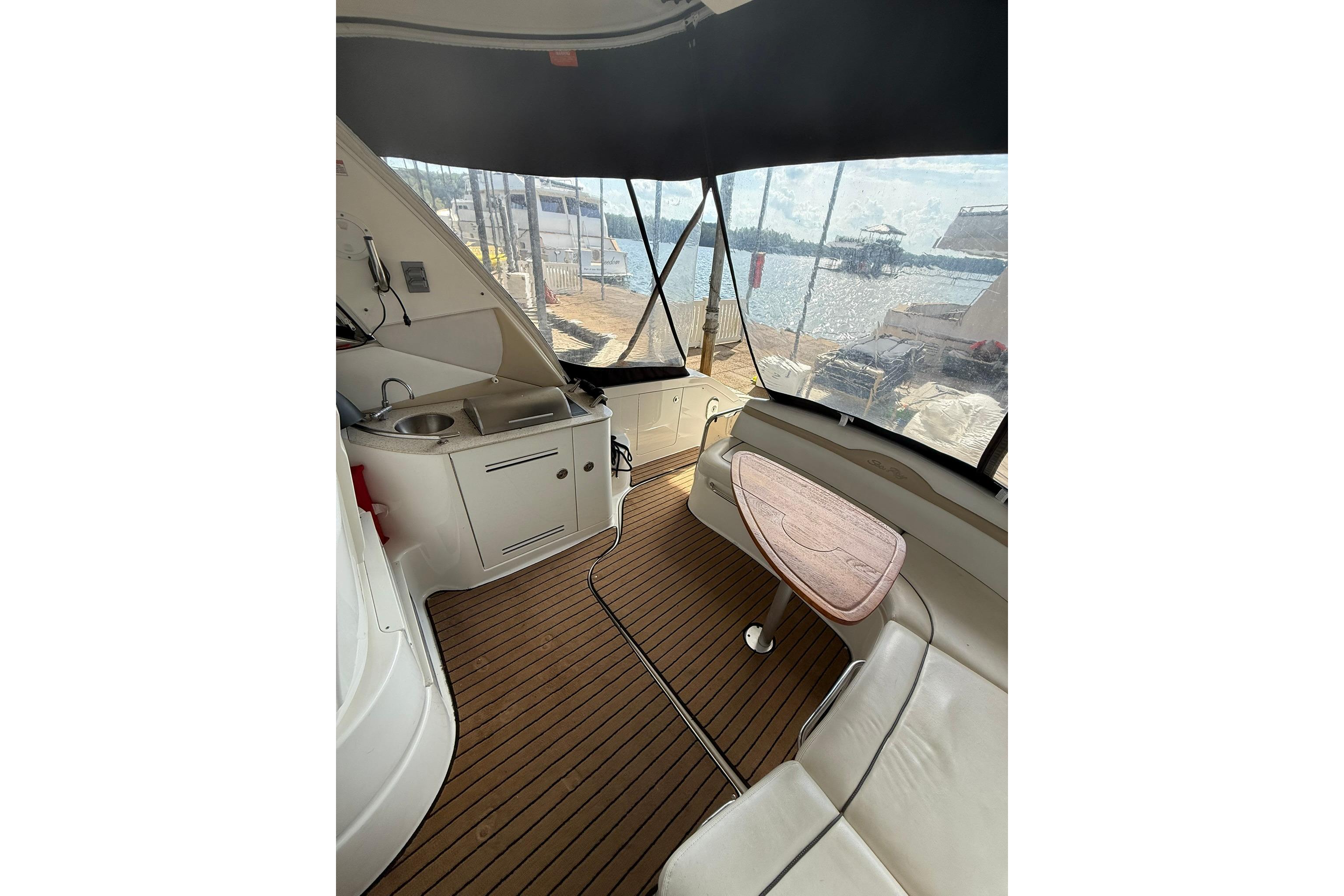 Interior of 2009 Sea Ray 350 Sundancer yacht with seating and kitchenette, docked by the water.
