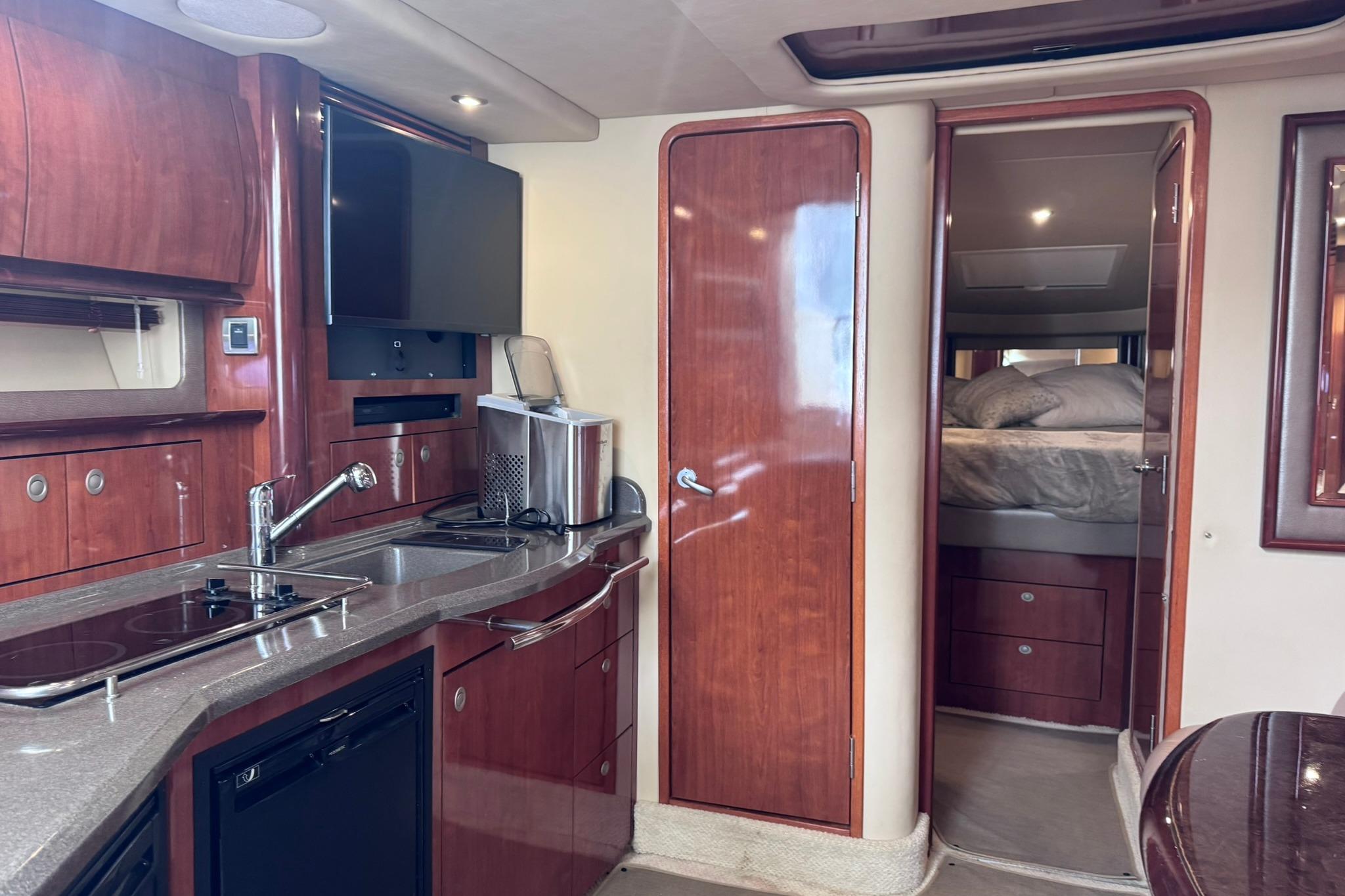 Luxurious interior of 2004 Sea Ray 390 Sundancer yacht with modern kitchen and cozy bedroom.