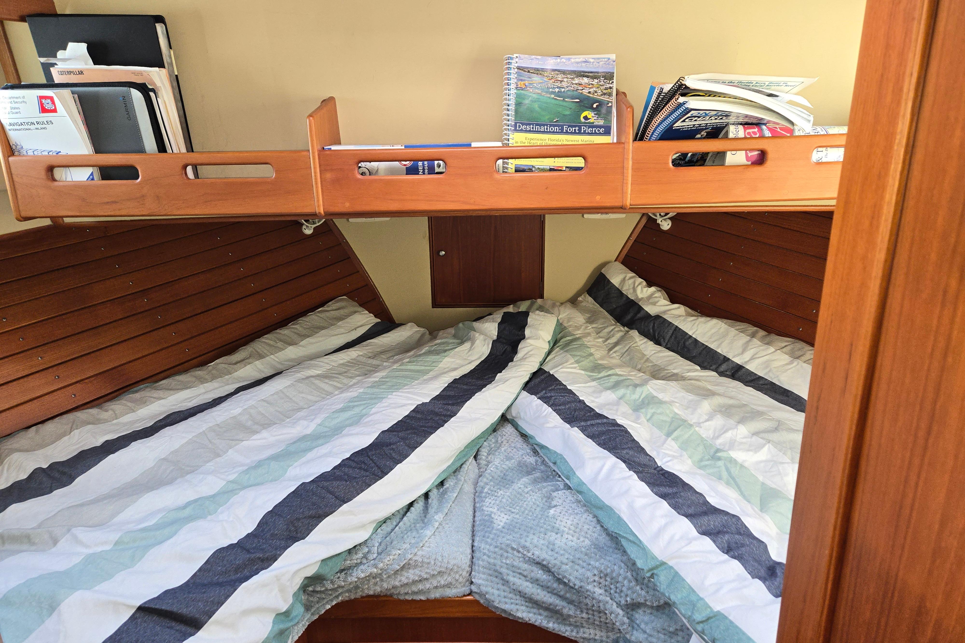 Cozy cabin interior of 1992 Grand Banks 46 Classic yacht with striped bedding and wooden shelves.