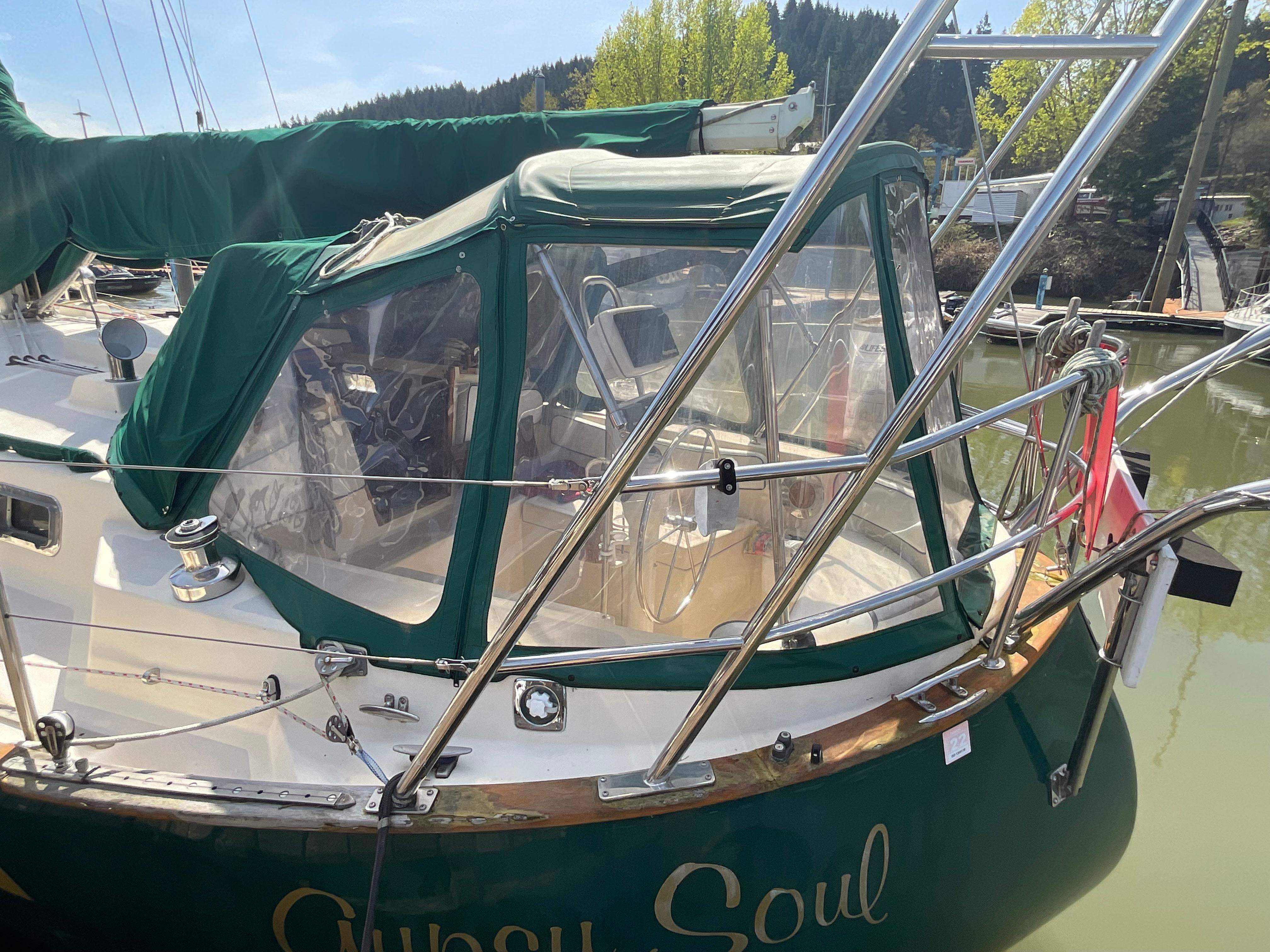 1984 Clearwater Cutter sailboat with green canopy docked in a marina.
