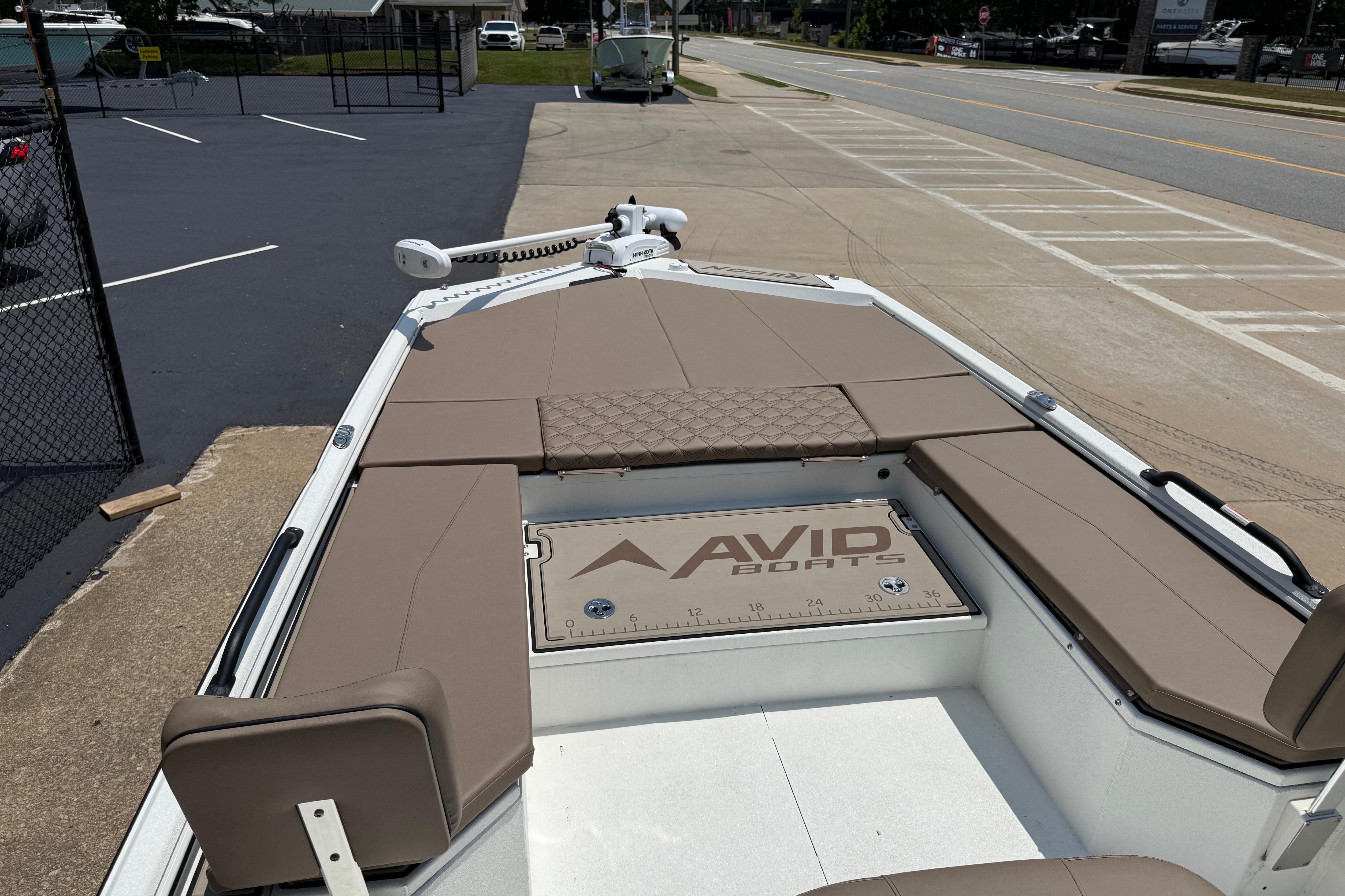 2025 Avid 22 Recon boat with tan seating, parked near a road.