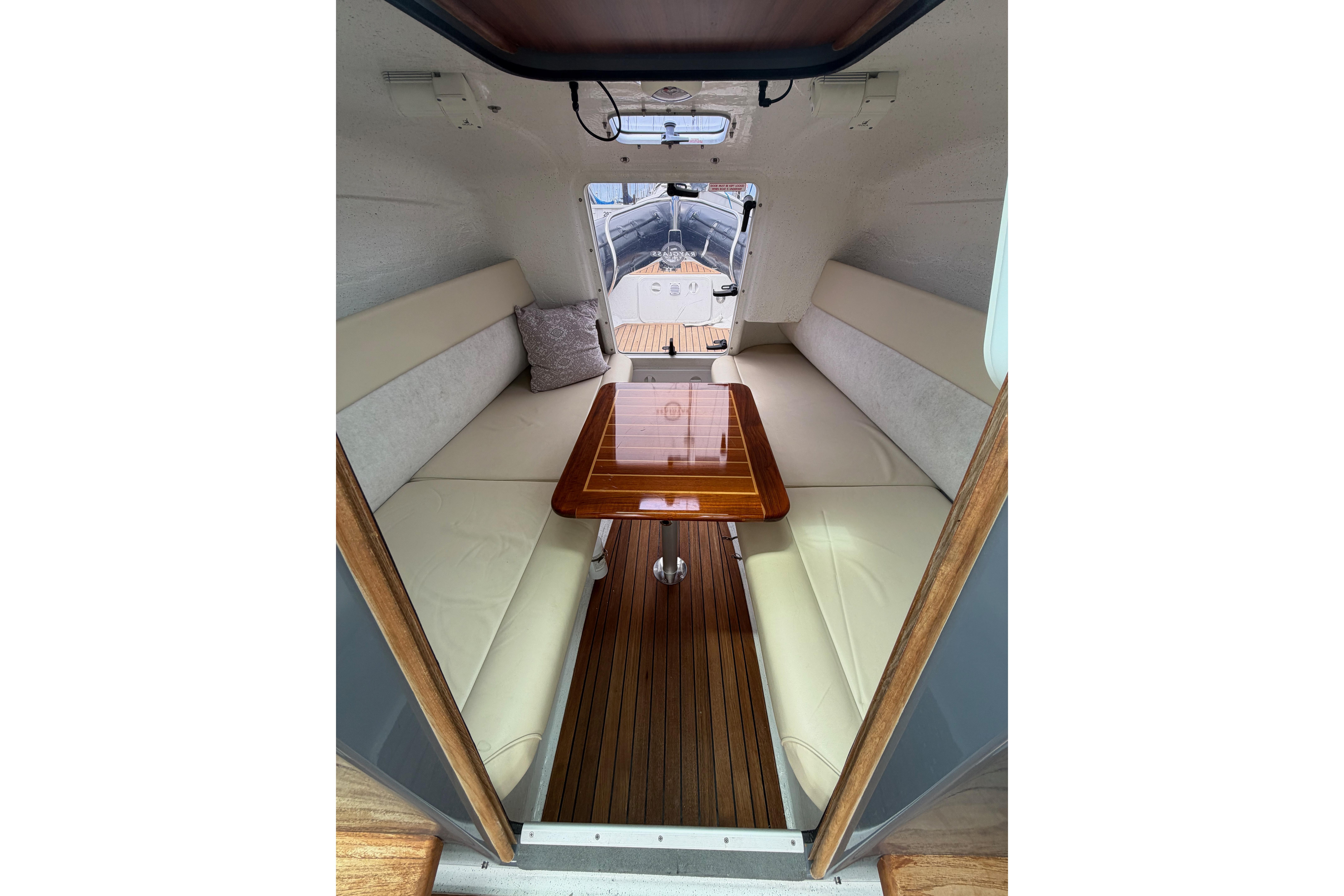 Interior of 2016 Protector Targa 30 boat with wooden table and cushioned seating.