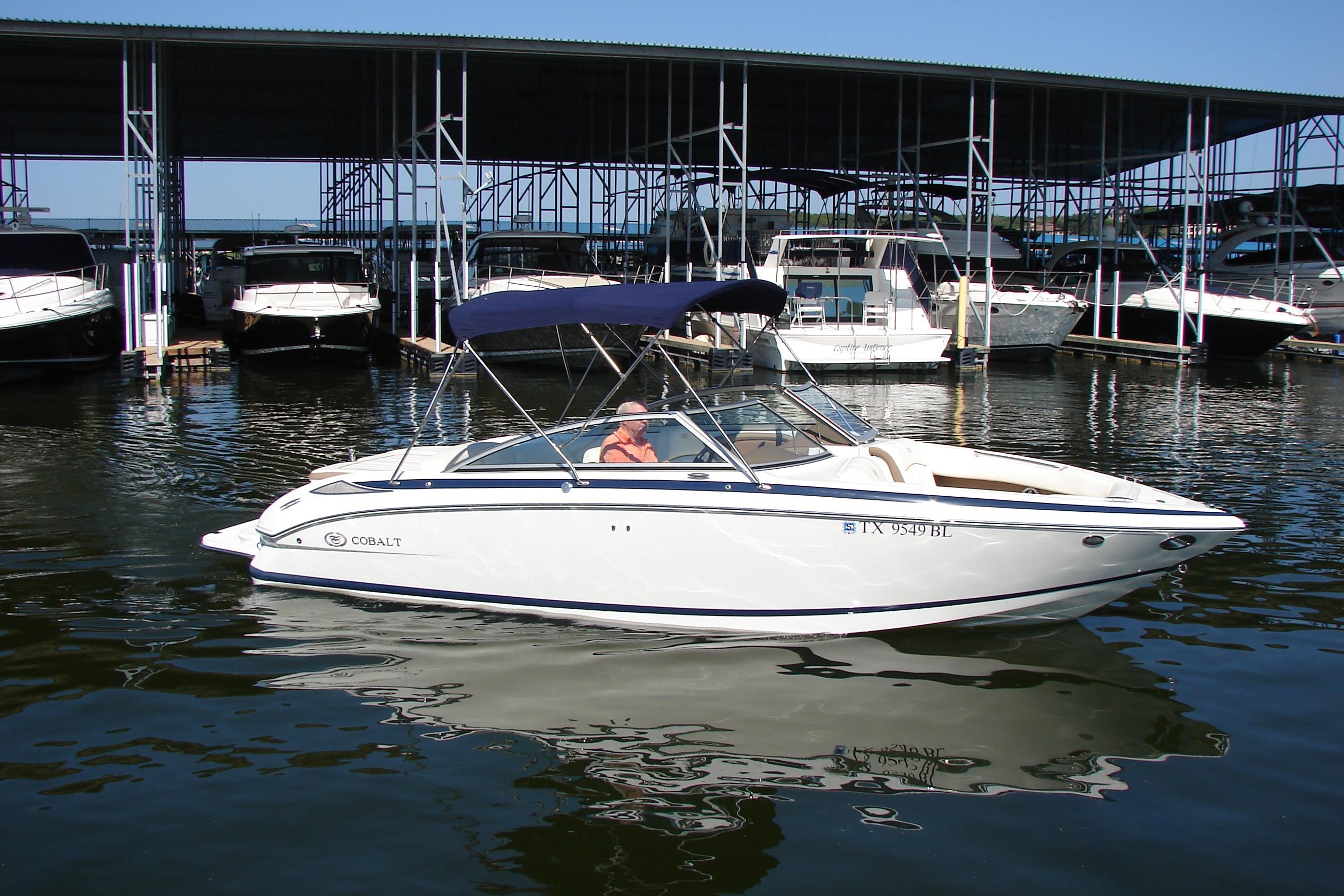 2011 Cobalt 232 boat docked in marina, featuring sleek design and blue canopy.