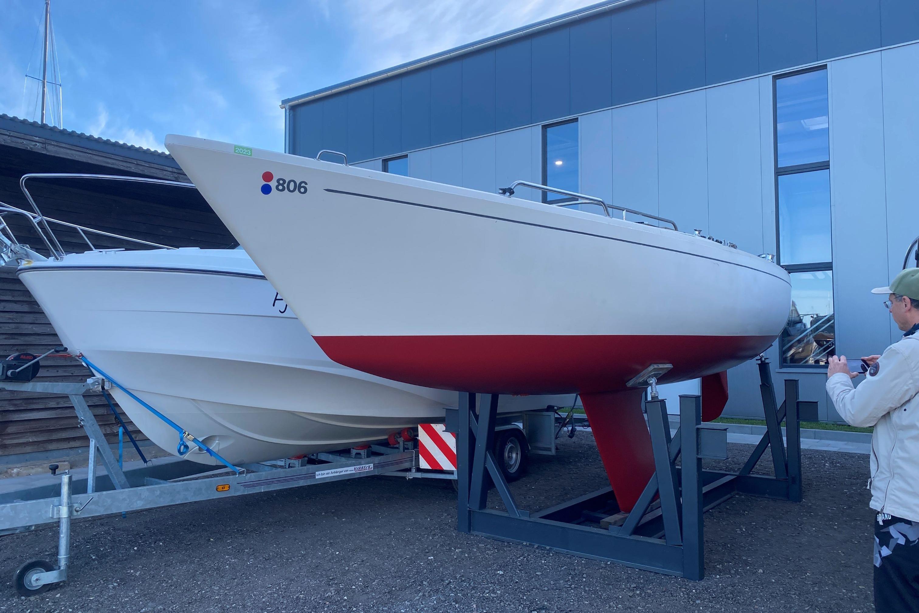 1977 O.L.-Bats International 806 sailboat on trailer, parked outside modern building.