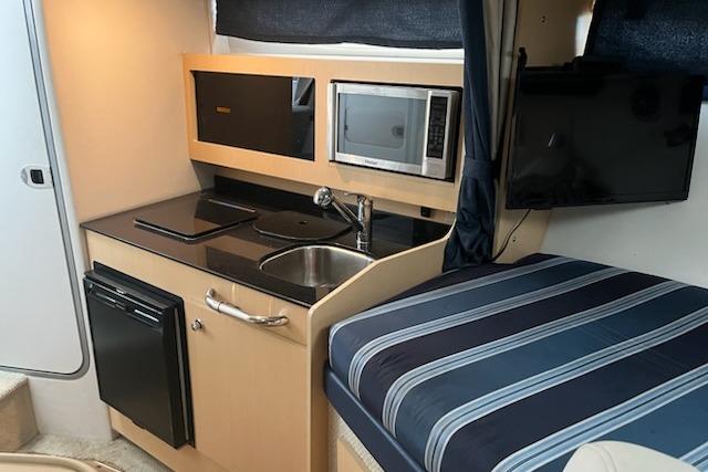 2012 Bayliner 285 Cruiser interior with kitchenette, microwave, sink, and striped bedding.