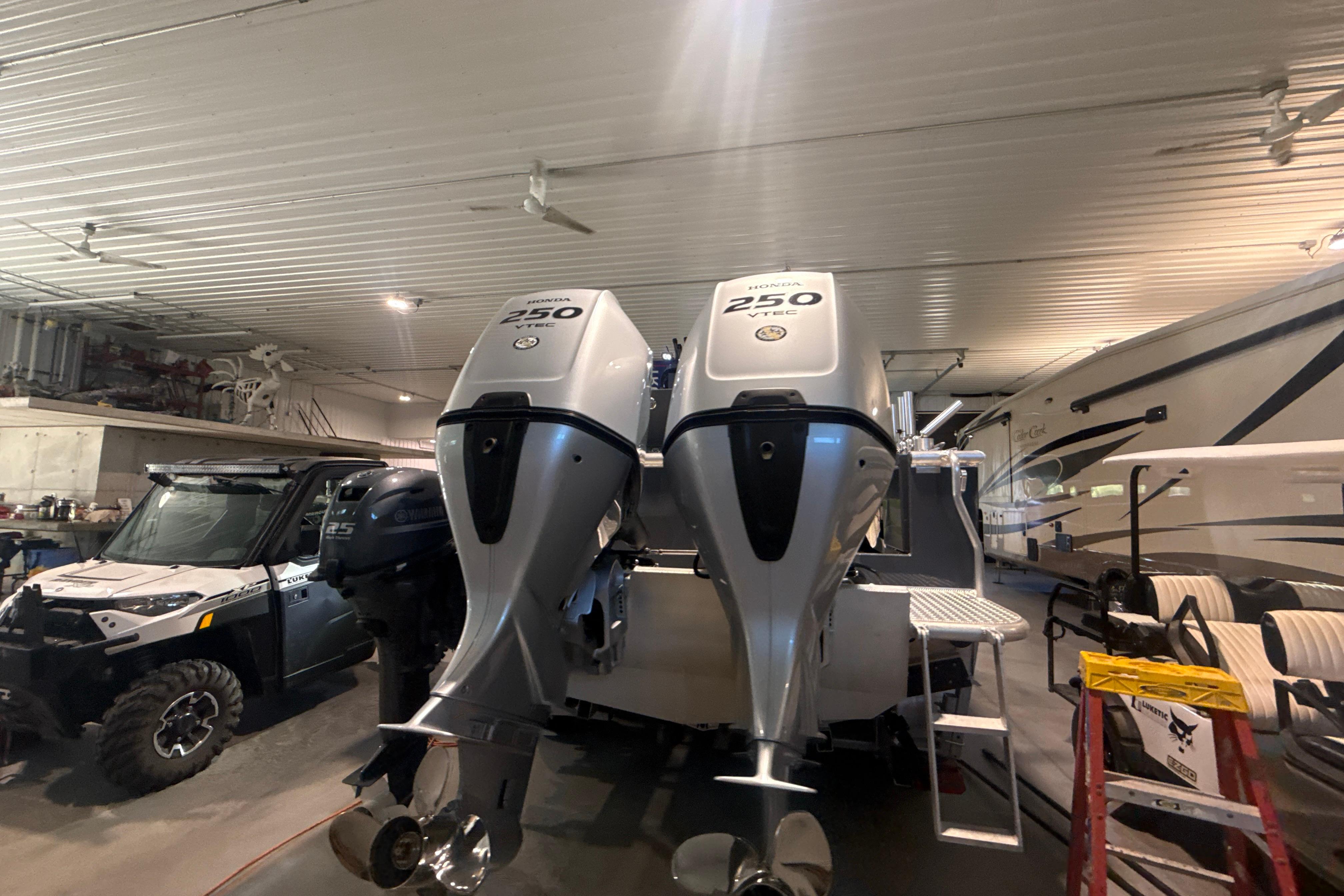 2022 Hewescraft 270 Alaskan Hardtop with dual Honda 250 outboard engines in a garage.