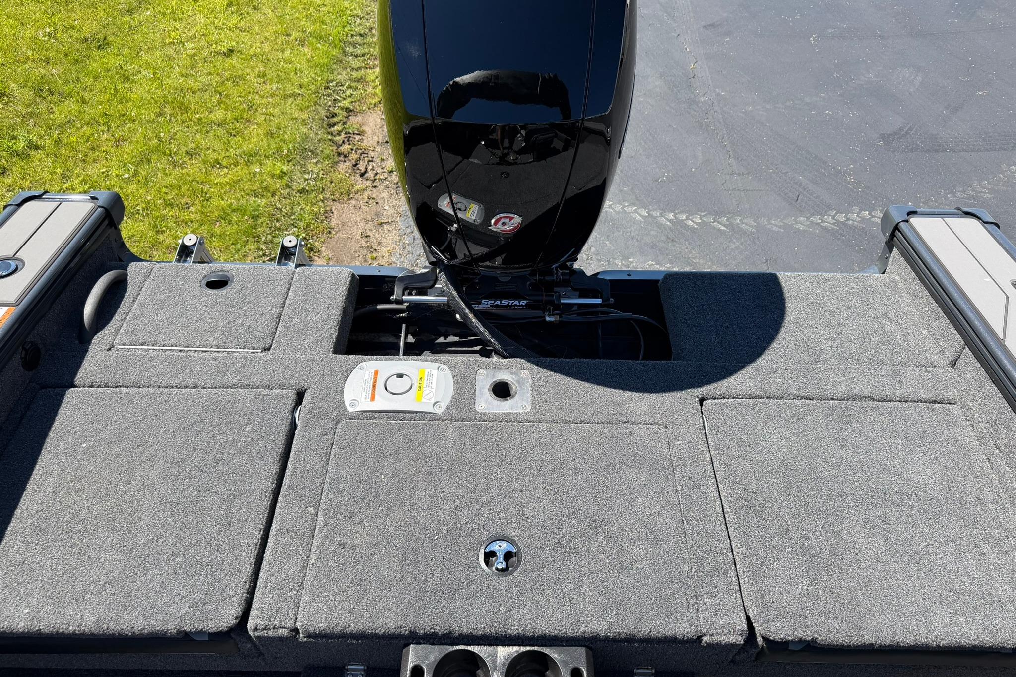 2027 Lund 1775 Crossover XS boat deck with motor, featuring carpeted surface and storage compartments.