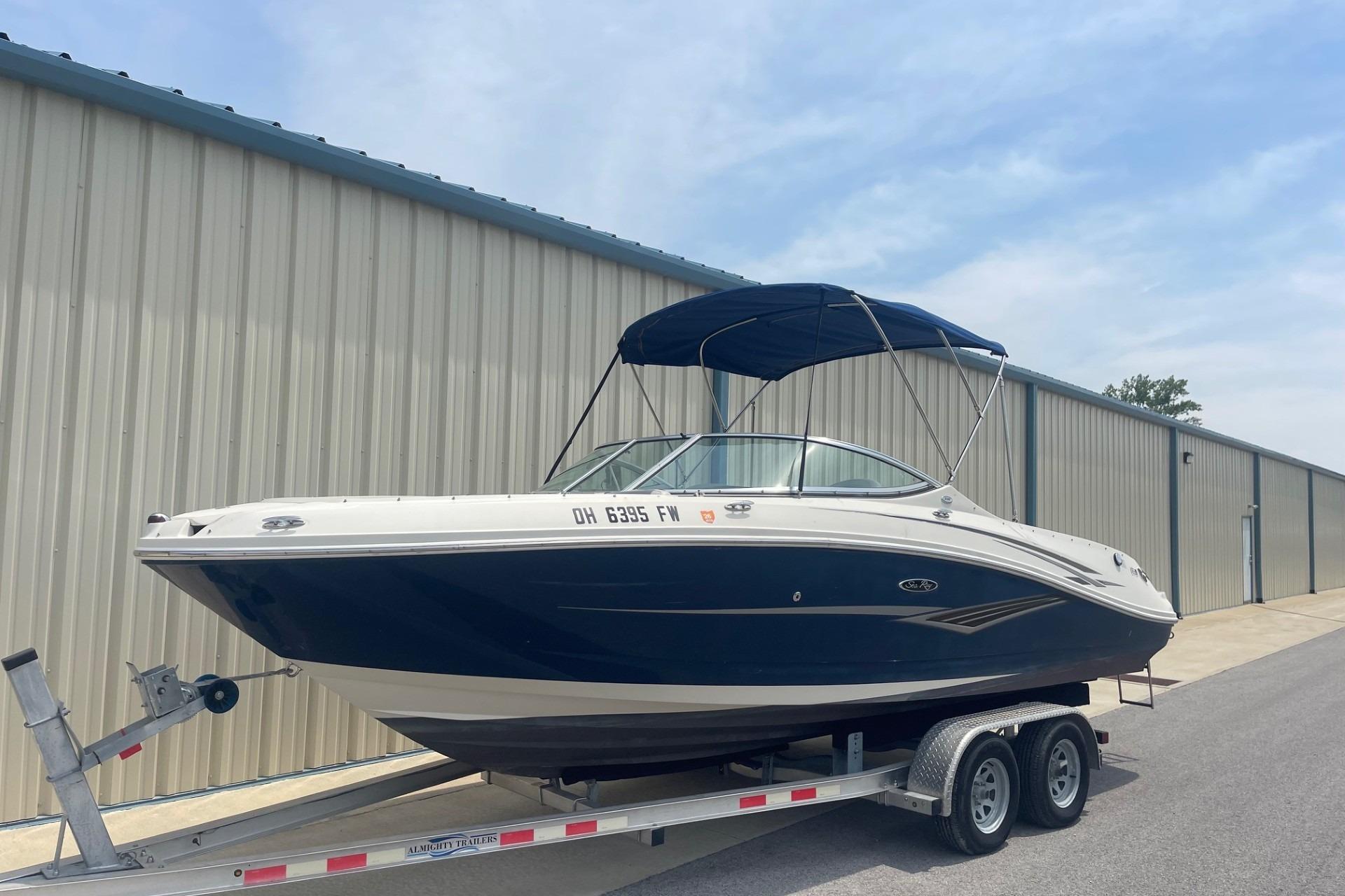 2010 Sea Ray 230 Bow Rider Select on trailer, parked near a metal building.