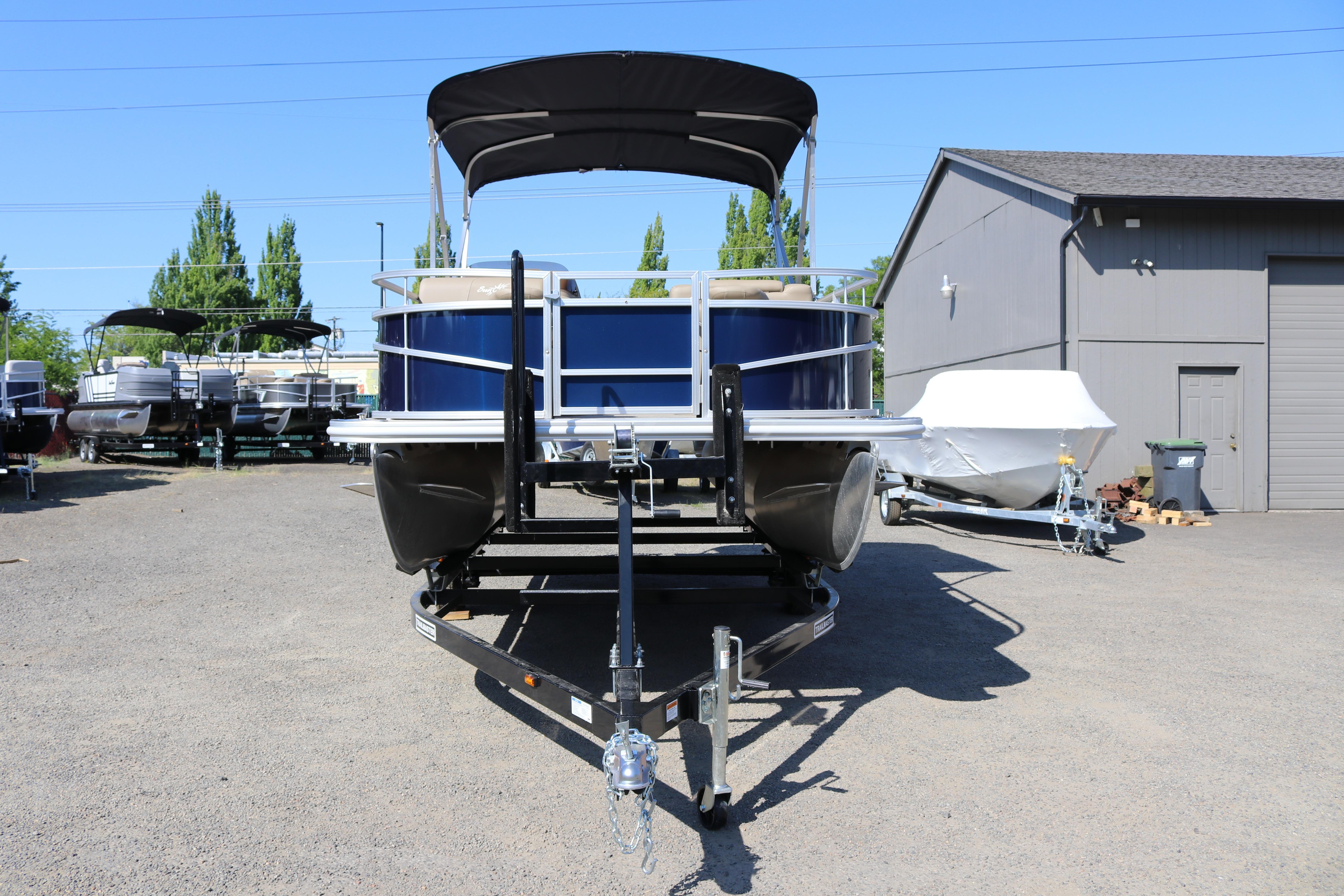 2025 Sun Chaser Vista Fish 18 pontoon boat on trailer, parked outdoors.