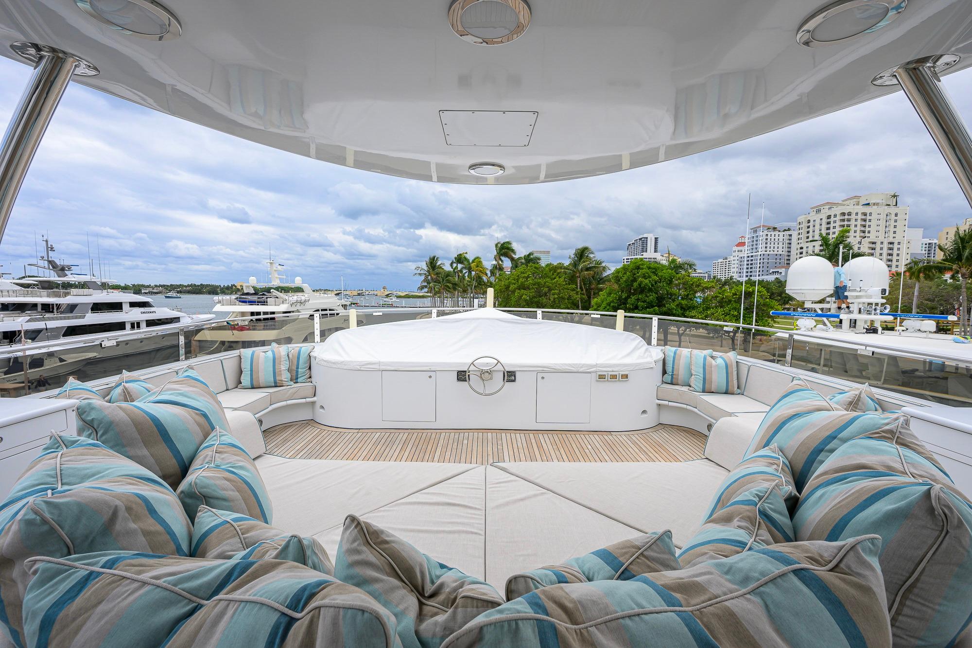 Luxurious 2003 Cheoy Lee Trideck yacht deck with plush seating and scenic marina view.