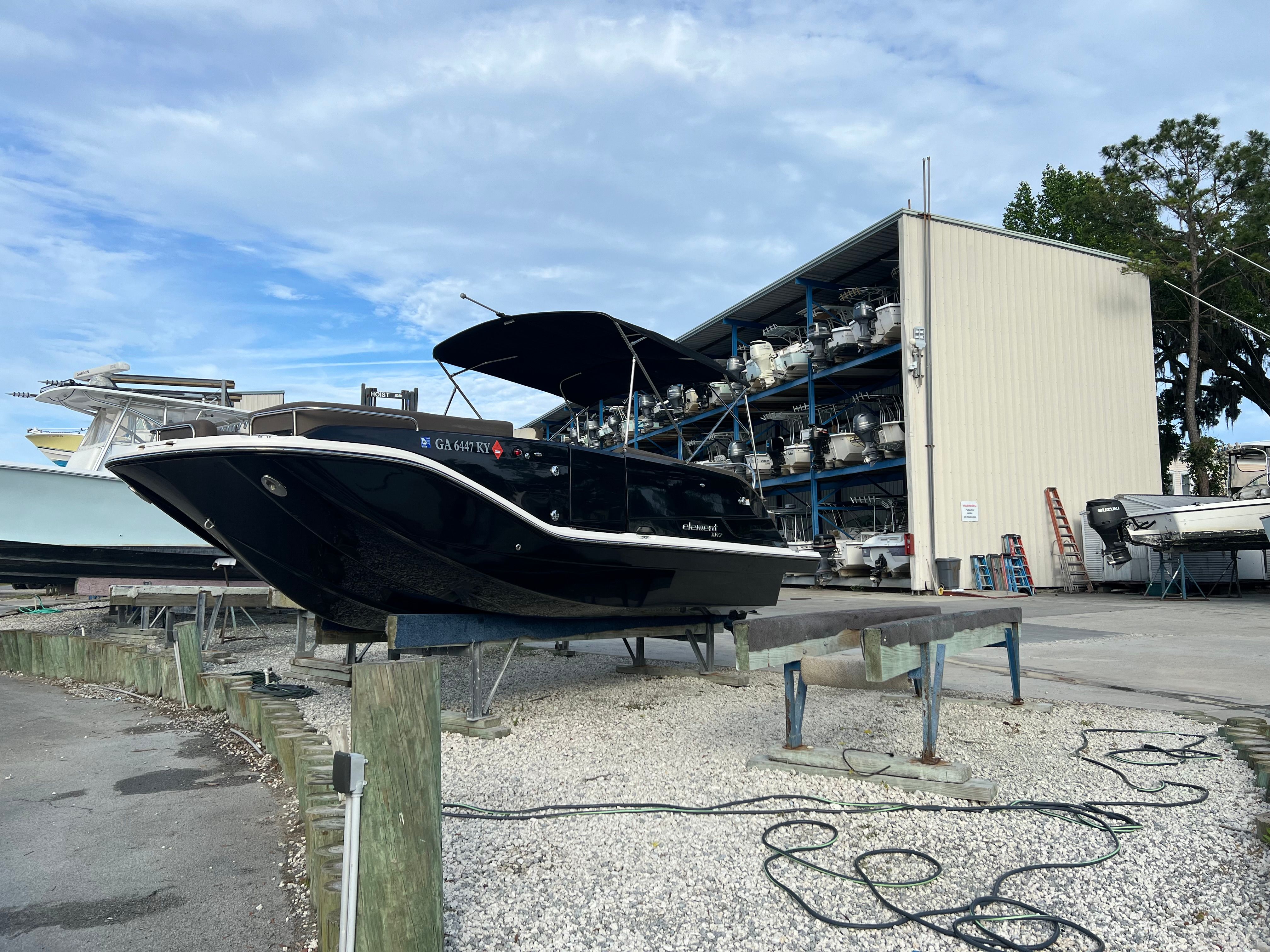 A 2019 Bayliner Element XR7 is on a boat stand in a marina area.