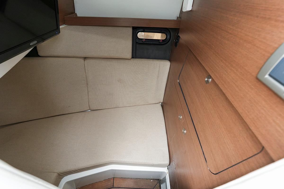 2018 Sea Ray SLX 350 cabin interior with beige seating and wooden cabinetry.