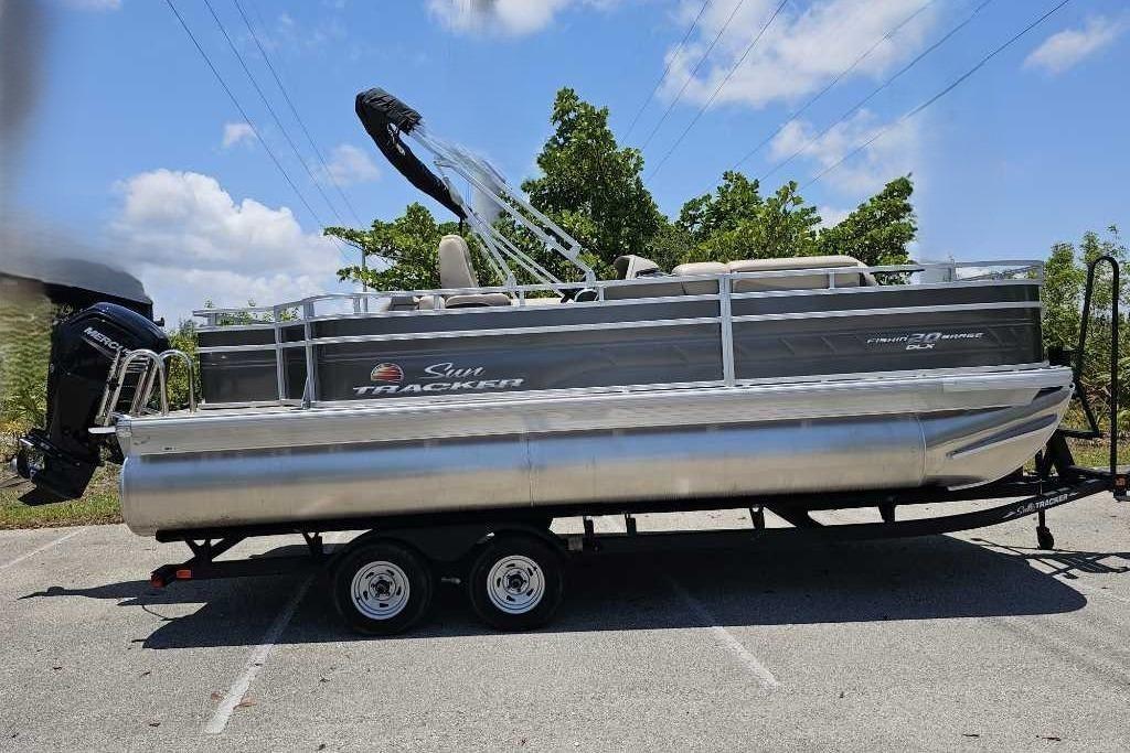 2025 Sun Tracker SportFish 20 DLX pontoon boat on trailer, parked outdoors.