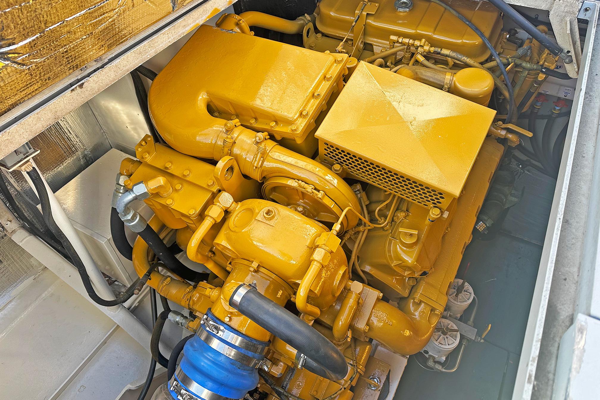 Engine compartment of a 1990 Boston Whaler 36 Defiance, showcasing a yellow marine engine.