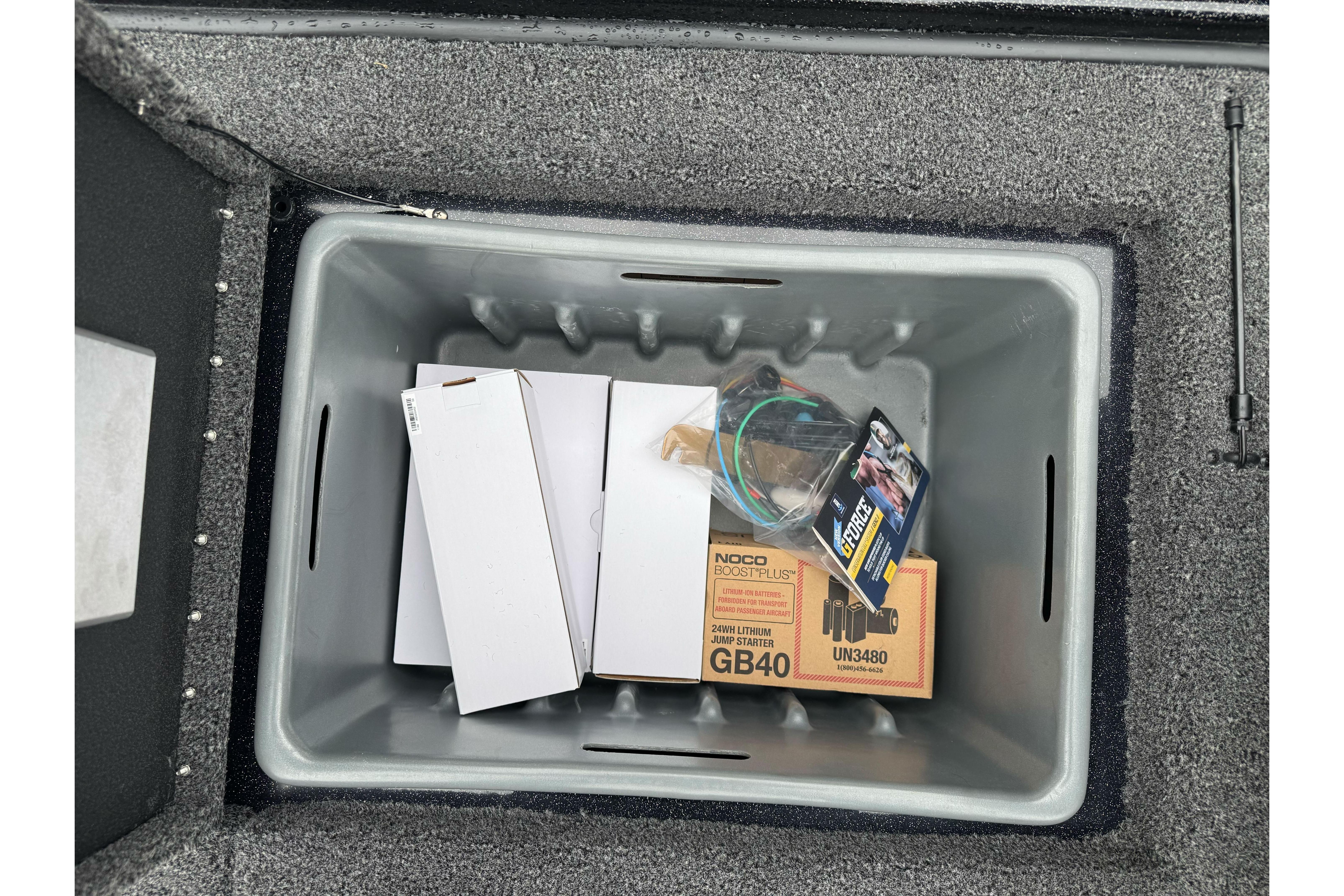 Storage compartment in 2026 Nitro Z20 XL Pro boat with various items, including a NOCO jump starter.