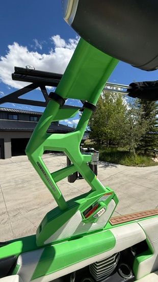 Green boat tower with mounts, parked outdoors in front of a building.