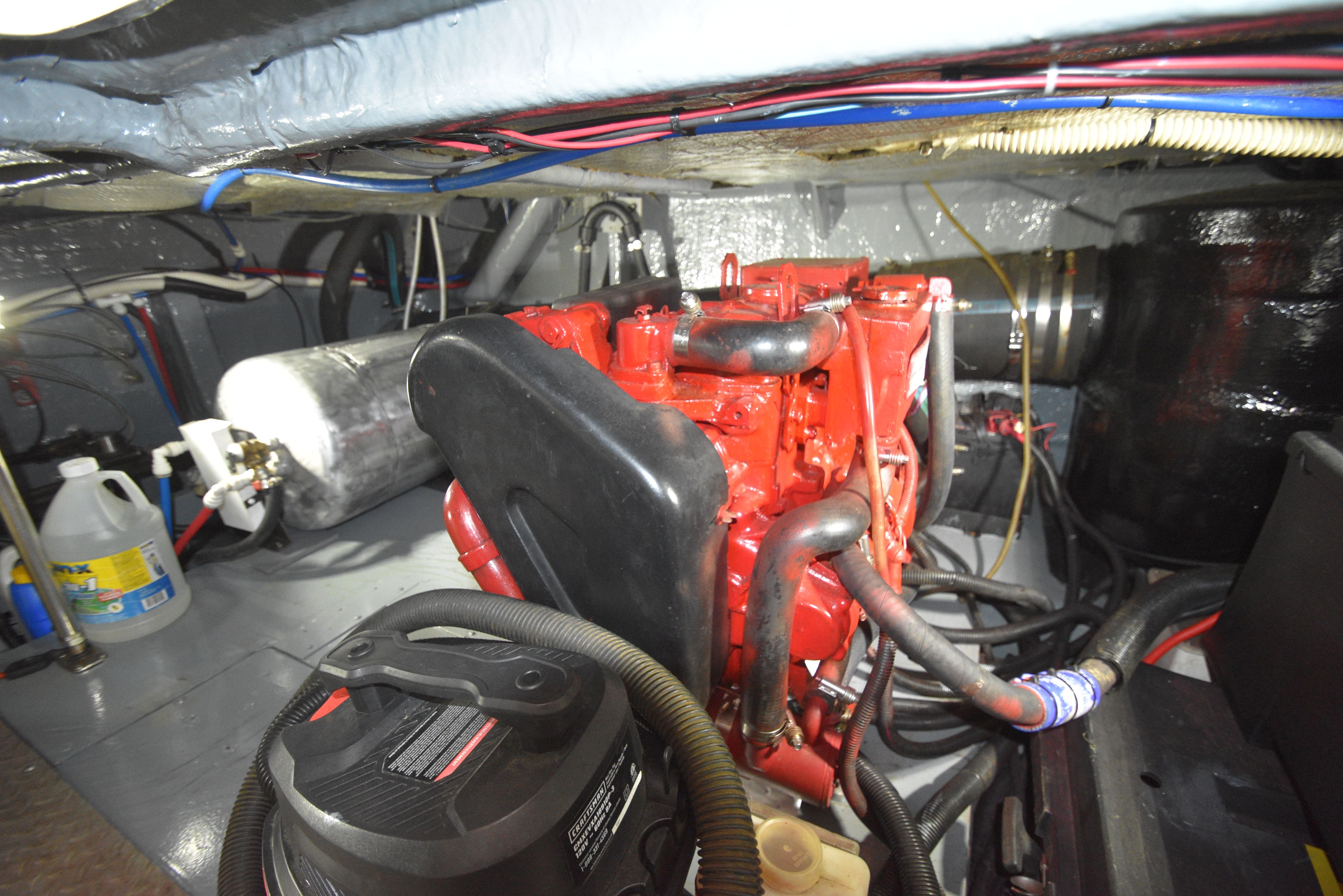 Engine room of 2000 Sea Ray 480 Sedan Bridge with red engine and hoses.