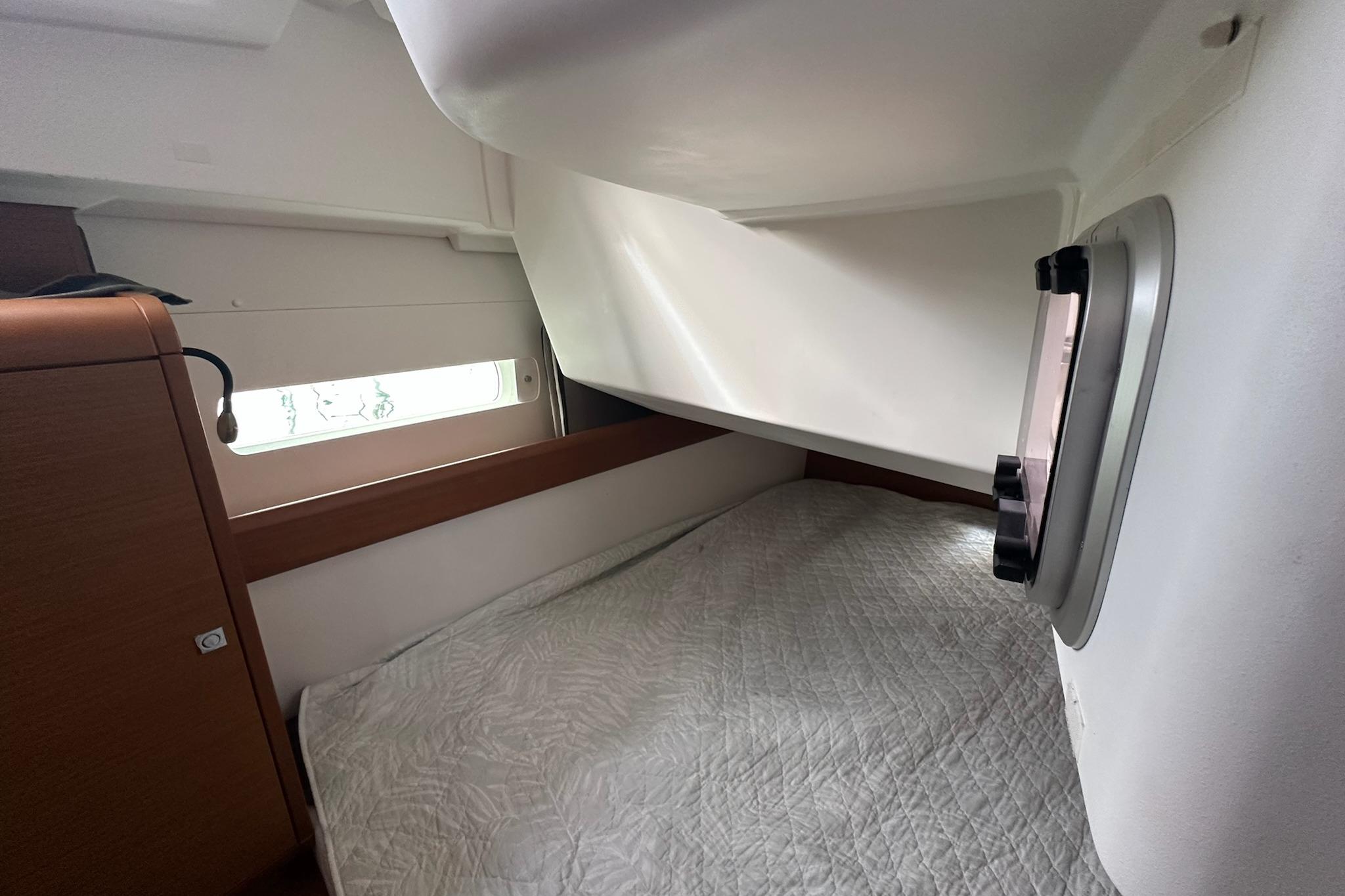 Cozy cabin interior of 2018 Jeanneau Sun Odyssey 479 sailboat with bed and window.