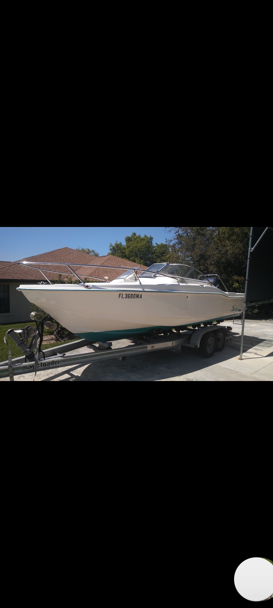 A 2000 Scout 202 boat on a trailer in a driveway.