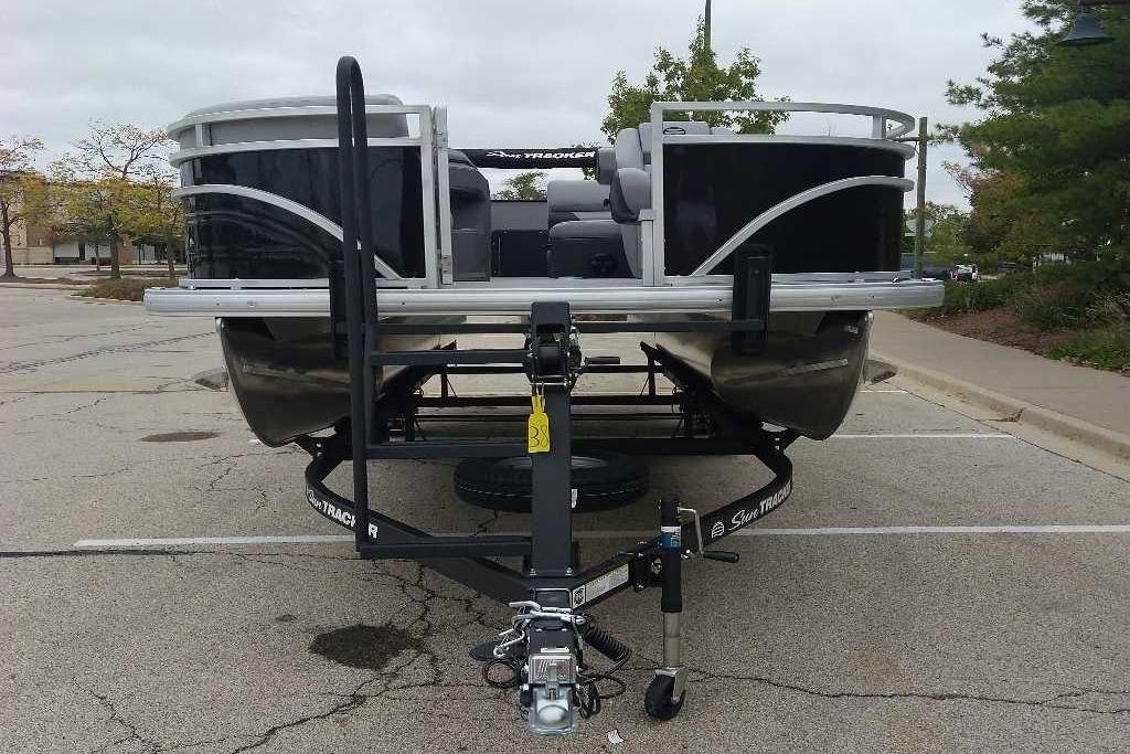2026 Sun Tracker SportFish 20 DLX pontoon boat on trailer in parking lot.