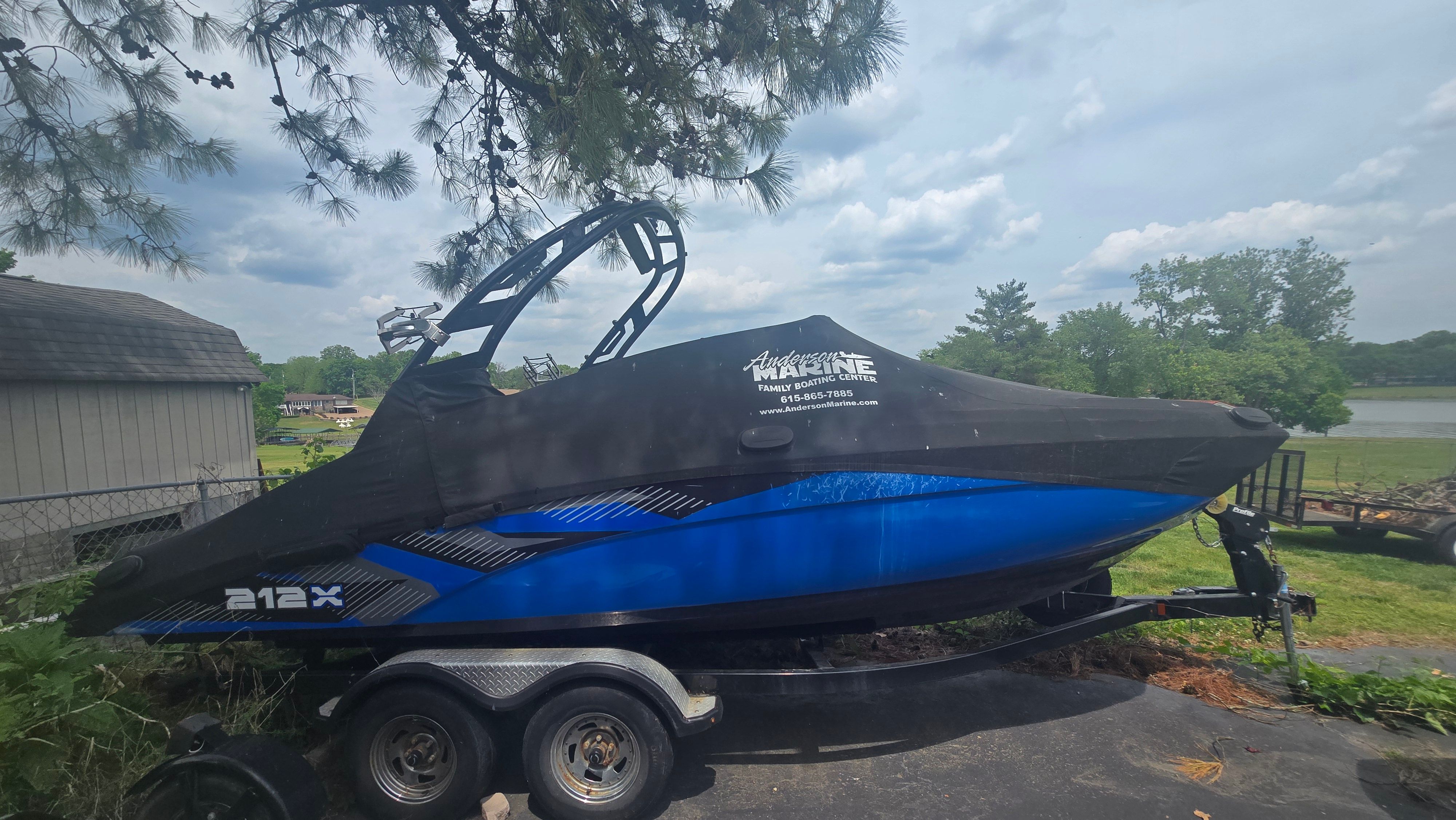 2017 Yamaha Boats 212X on trailer, blue and black, covered, parked outdoors.