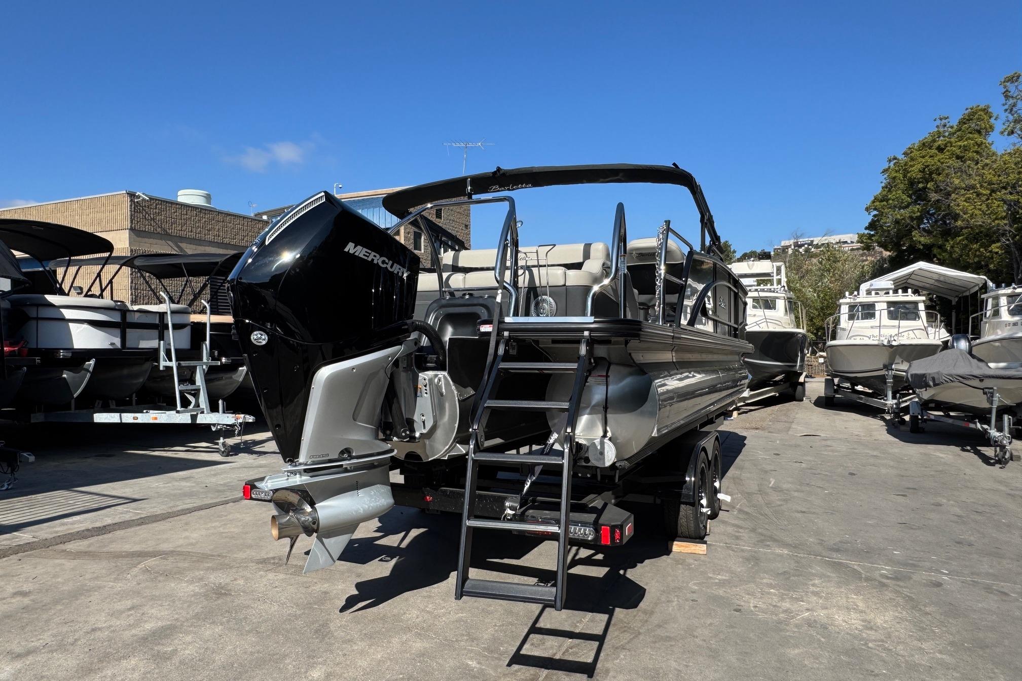 2026 Barletta Lusso 23UC pontoon boat with Mercury engine, parked outdoors.