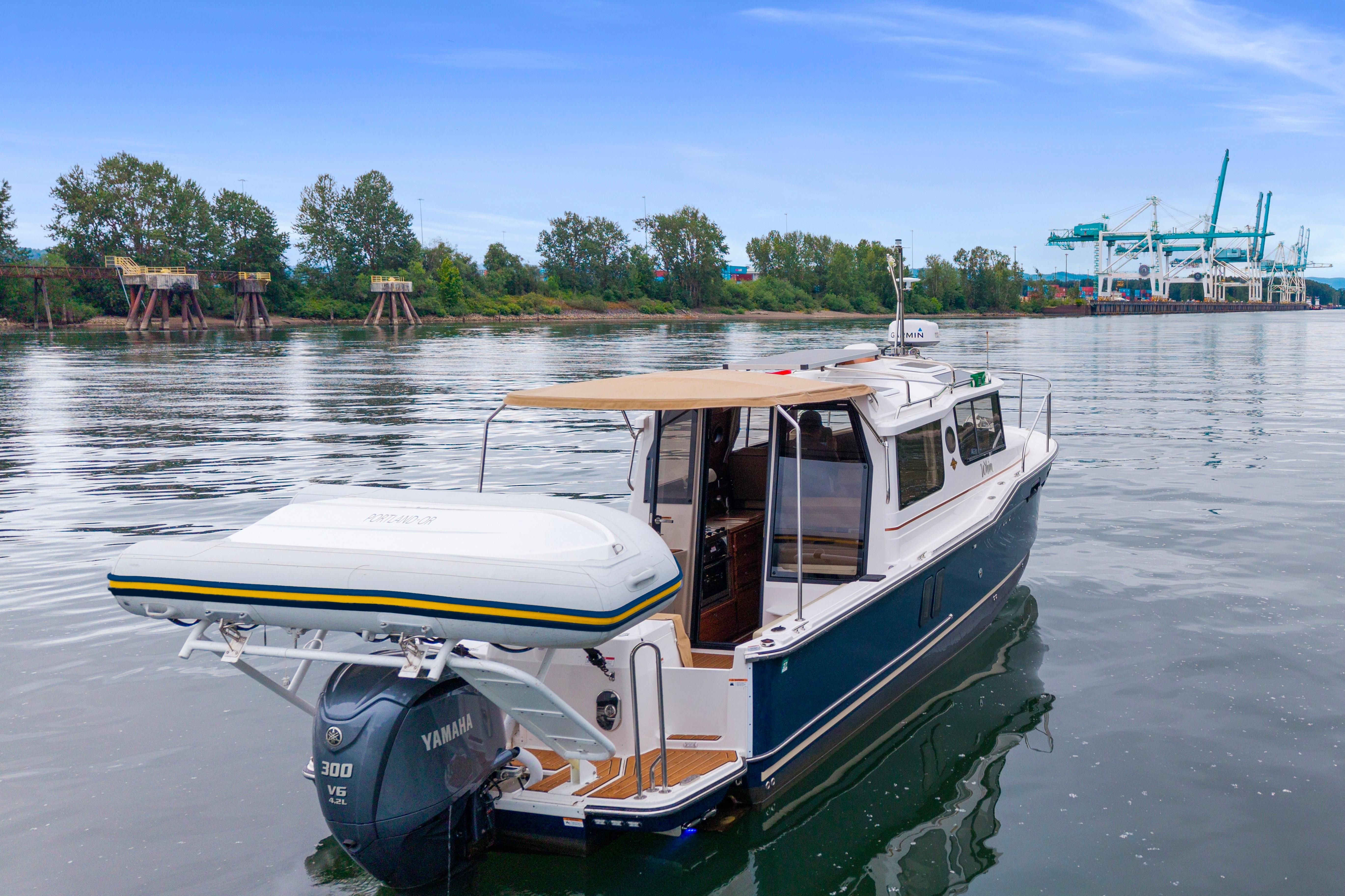 2022 Ranger Tugs R-27 boat on calm water near industrial docks.