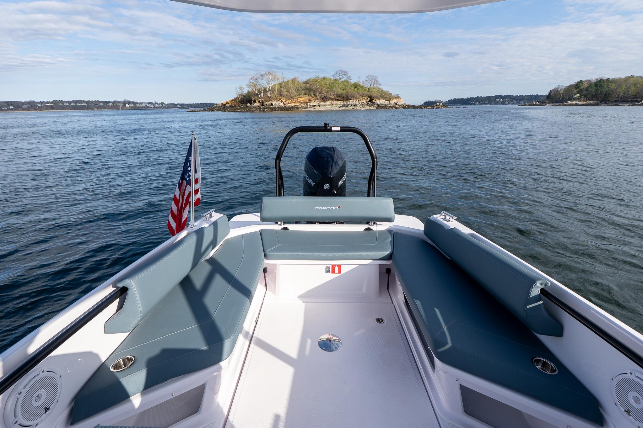 2025 Axopar Cross Top boat with seating, American flag, and scenic water view.