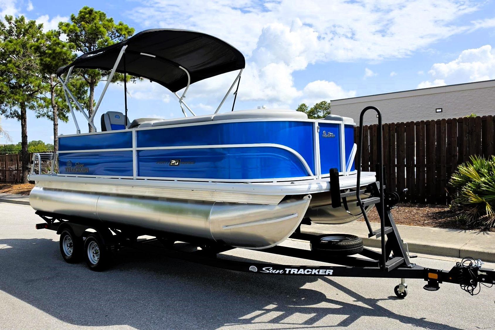 2026 Sun Tracker Party Barge 20 DLX pontoon boat on trailer, parked outdoors.