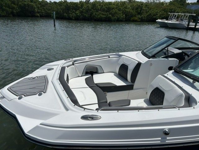 A sleek white boat with black accents sits on calm water.