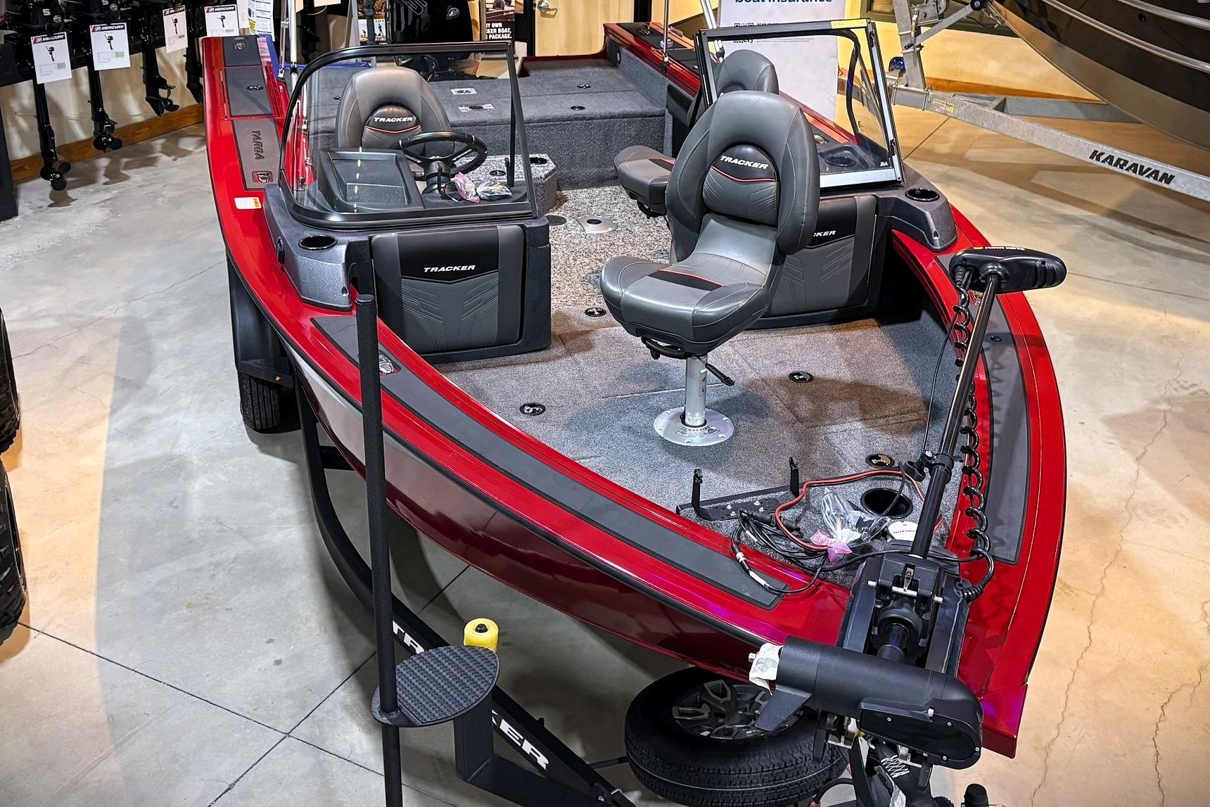 2025 Tracker Targa V-19 WT boat with red exterior and modern seating in showroom.