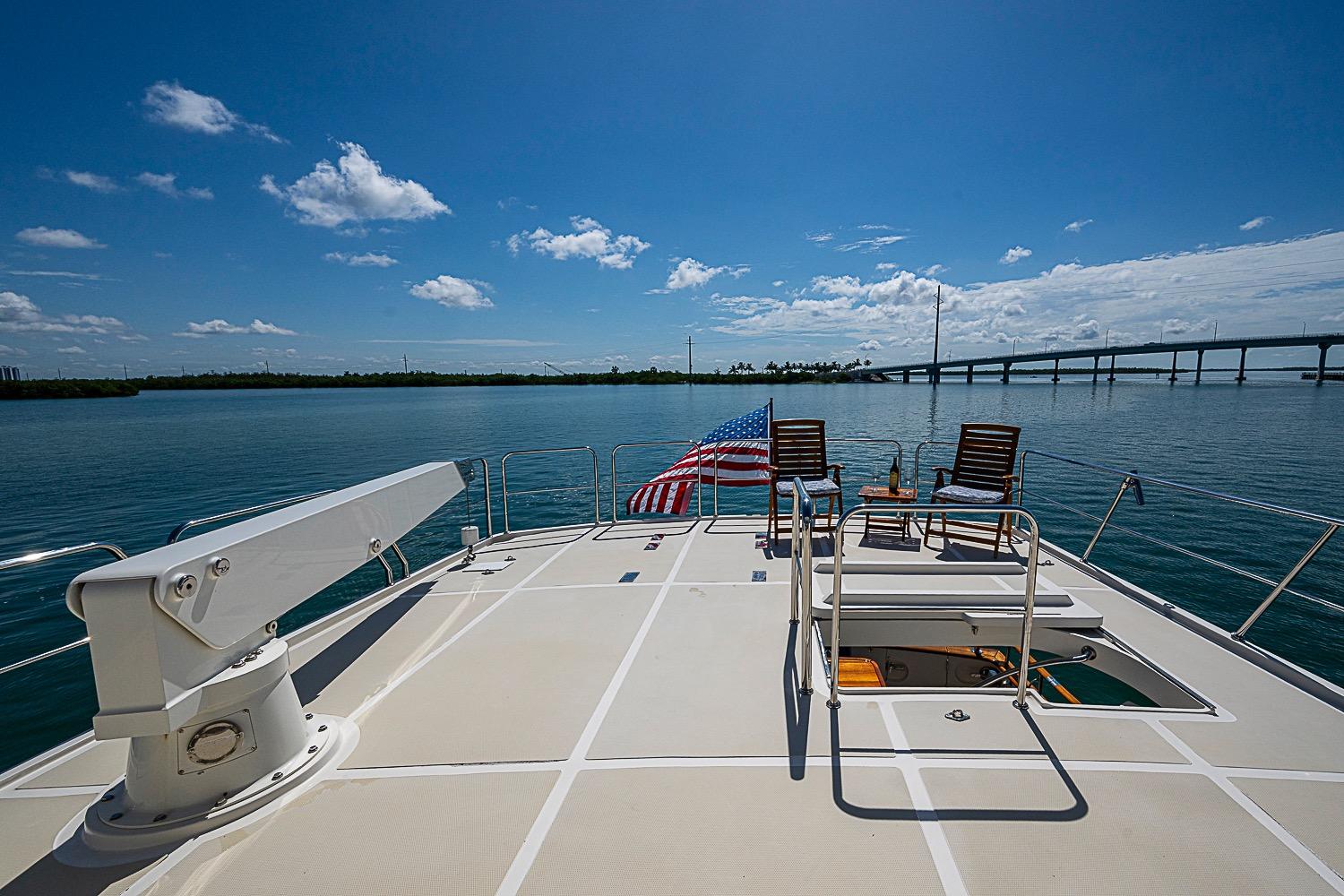 2014 Marlow 80 Explorer yacht deck with chairs, American flag, and ocean view.